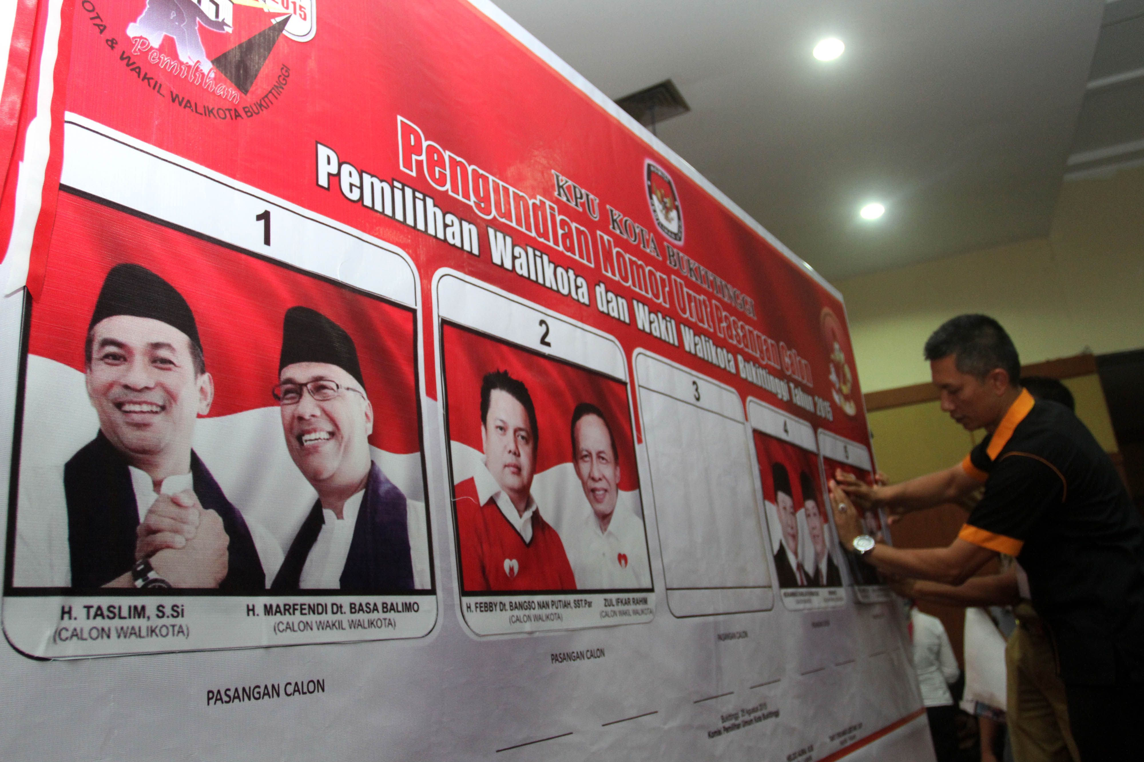  Seorang petugas menempelkan foto calon Wali Kota dan Wakil Wali Kota Bukittinggi hasil undian nomor urut peserta.