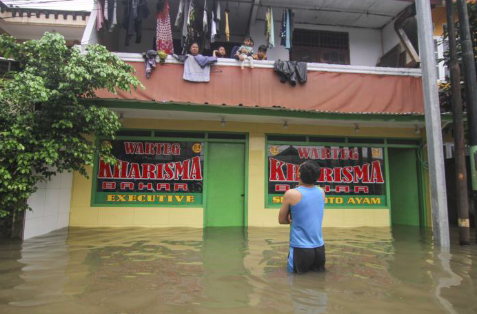 Sejumlah warga mengungsi di lantai dua rumahnya saat banjir di kawasan Kampung Makasar, Jakarta Timur, Selasa (25/2).  
