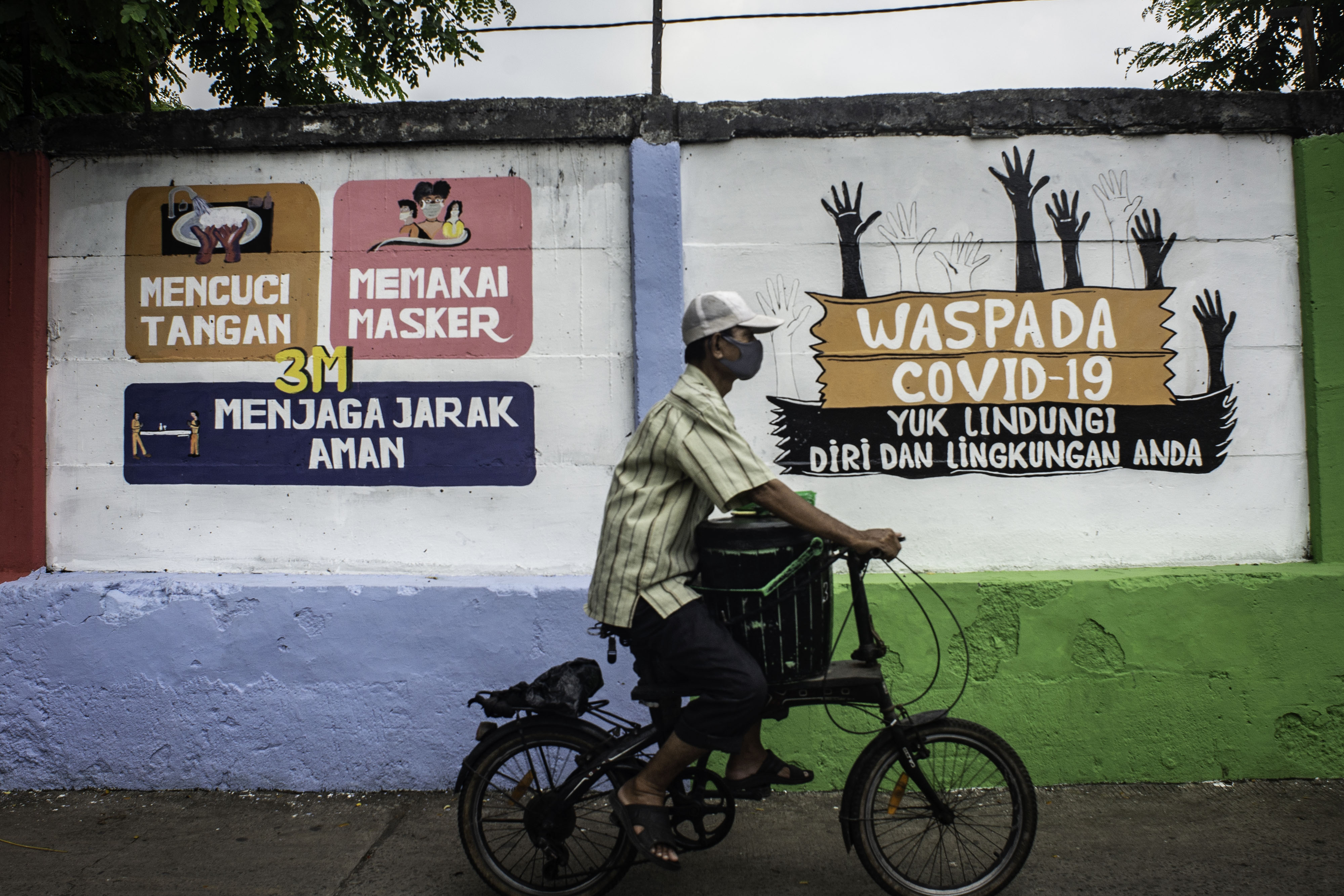 Warga melintasi mural terkait kampanye covid-19 di Petamburan, Jakarta.