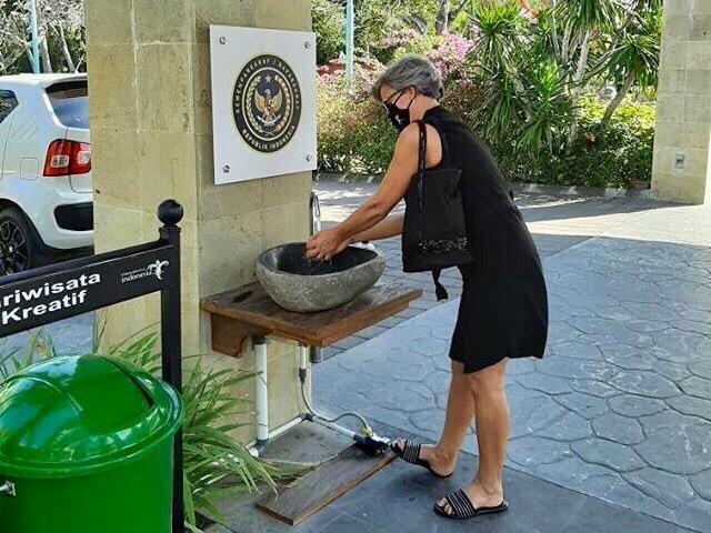 Turis mancanegara menerapkan protokol kesehatan dengan mencuci tangan sebelum masuk hotel di Bali.  