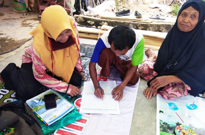 Pendamping IPDMIP membantu ketua kelompok tani (Poktan) beserta istrinya mengisi formulir ke perbankan 