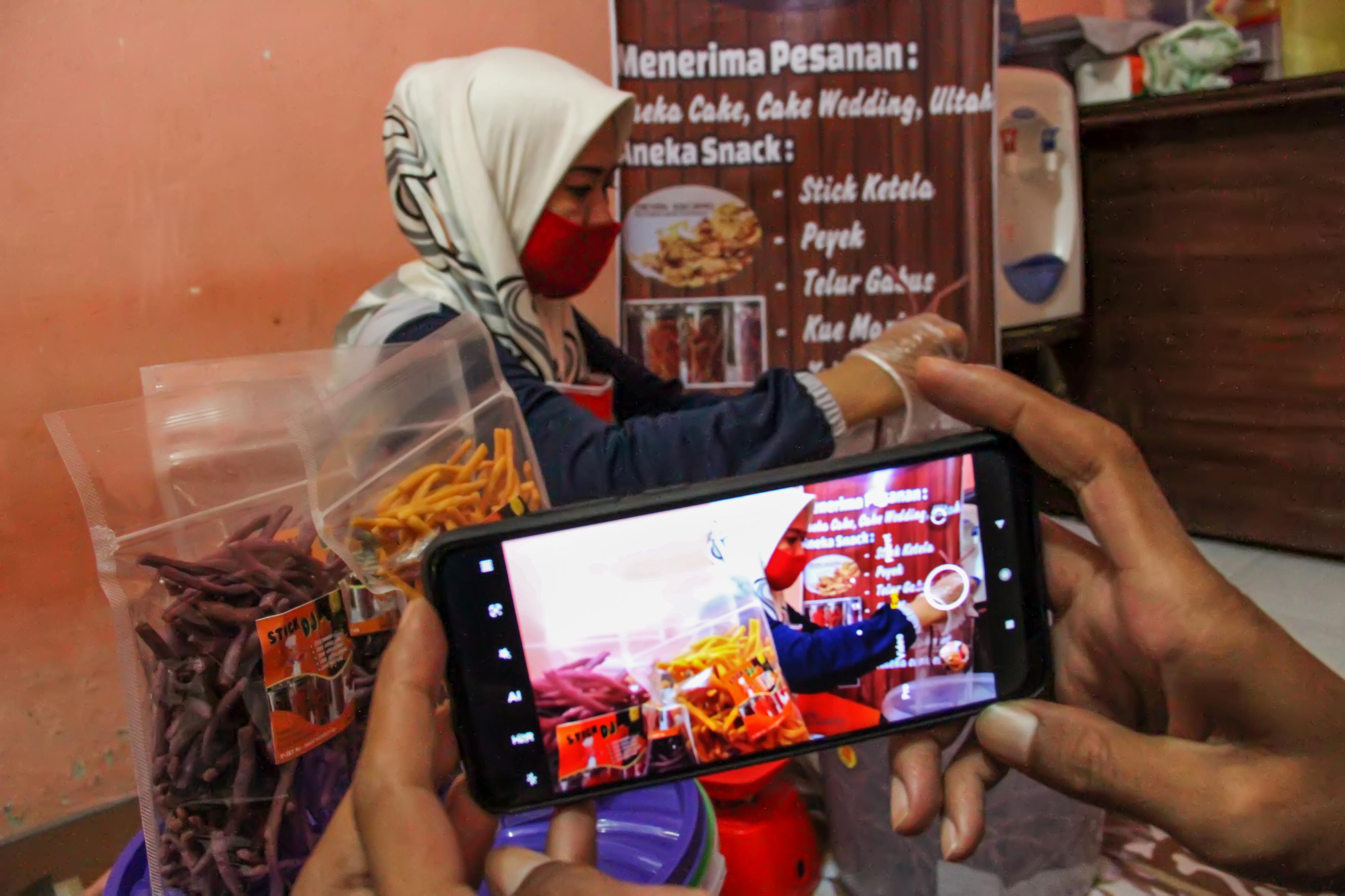  Pengusaha Usaha Mikro Kecil Menengah (UMKM) memotret produk makanan stik ketela untuk dipasarkan melalui media sosial.