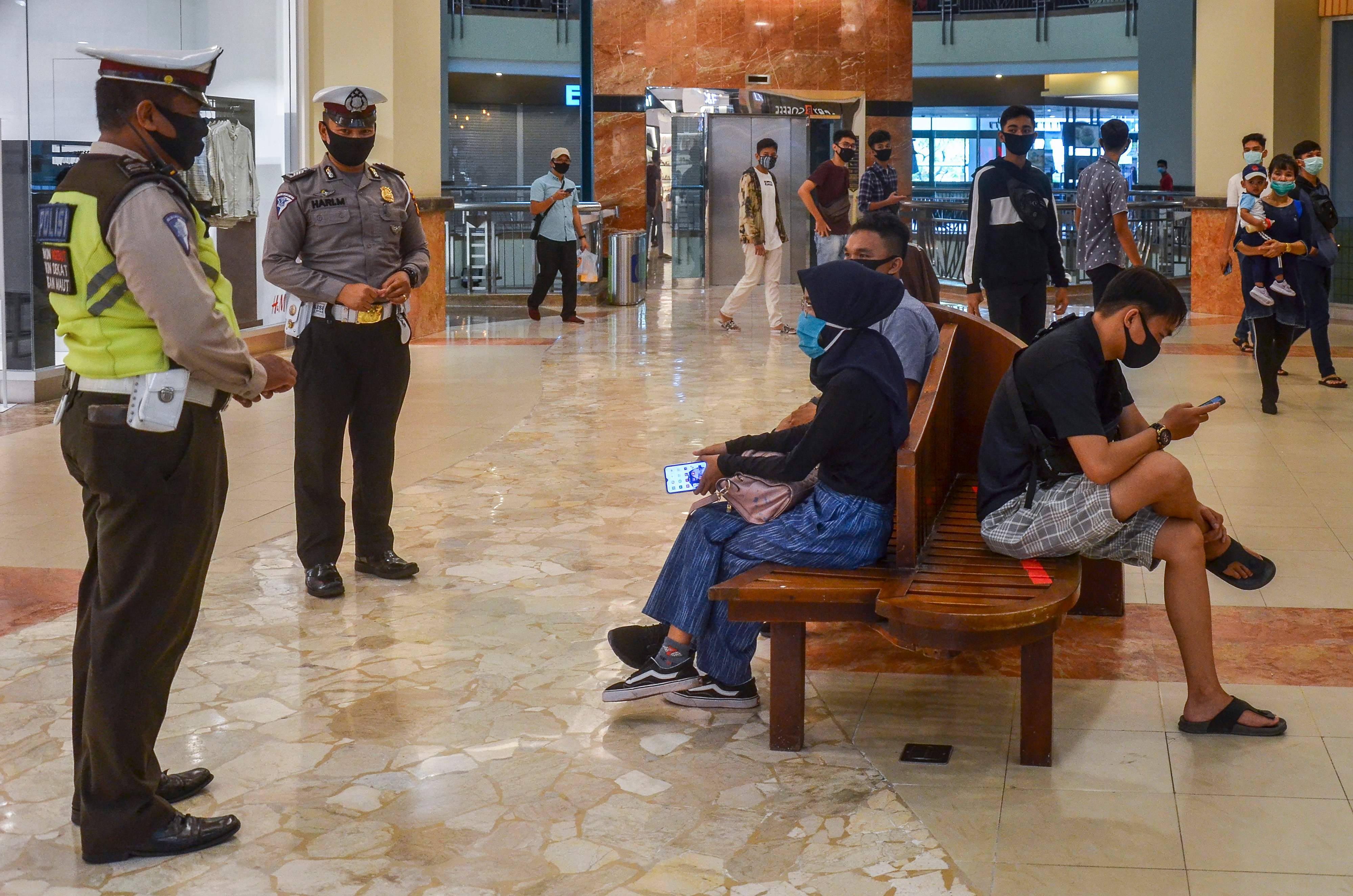 Polisi menjelaskan mengenai protokol kesehatan kepada warga yang berkunjung ke sebuah pusat perbelanjaan di Pekanbaru, Riau.