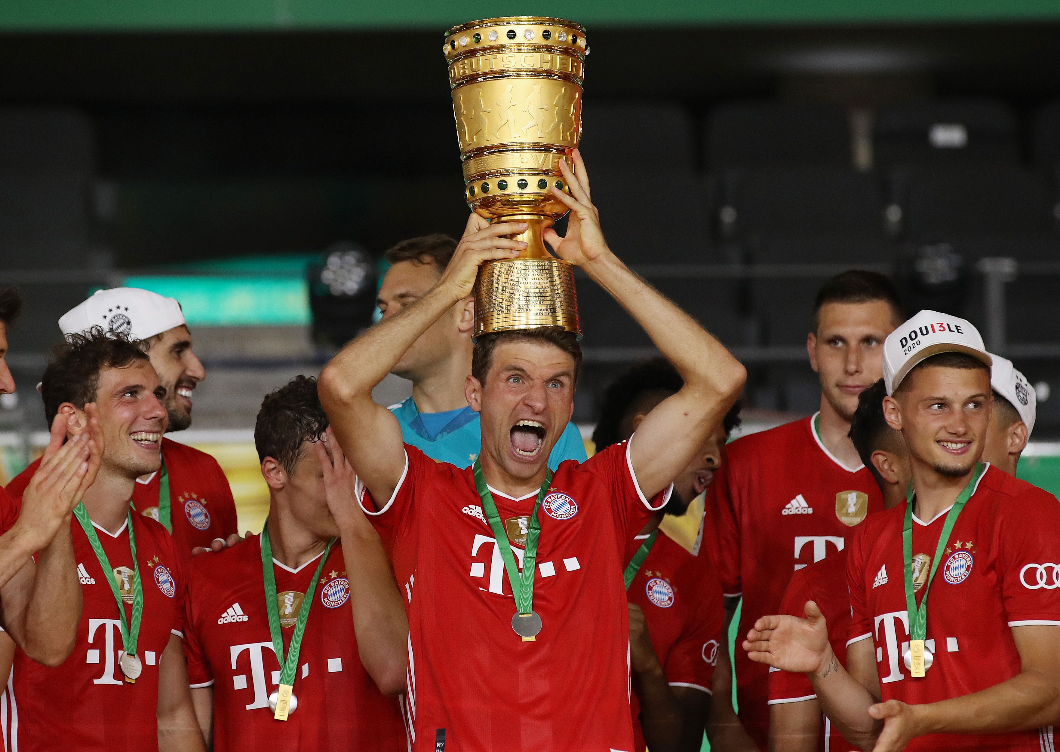 Penyerang Bayern Muenchen Thomas Mueller mengangkat trofi DFB Pokal musim 2019/20.