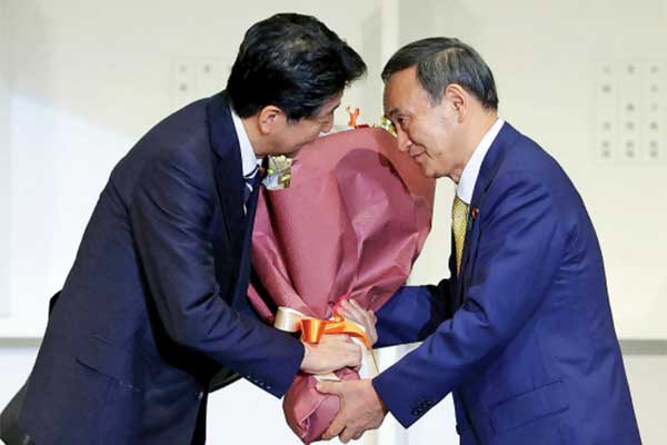 Yoshihide Suga (kanan) mempersembahkan bunga kepada Perdana Menteri (PM) Shinzo Abe seusai memenangi pemilihan 