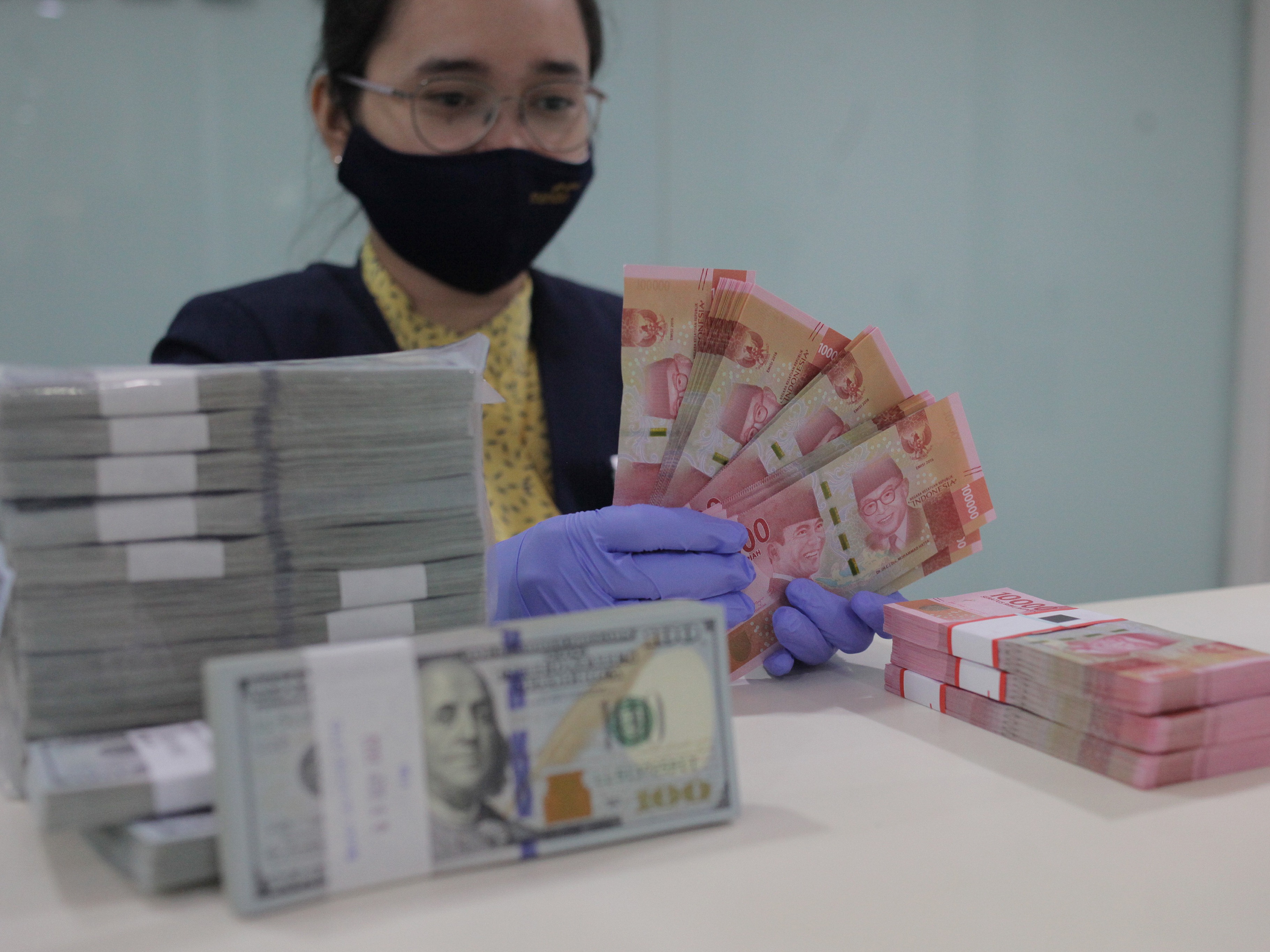 Karyawati menghitung uang rupiah dan dolar AS di salah satu bank di Jakarta, Kamis (10/9).