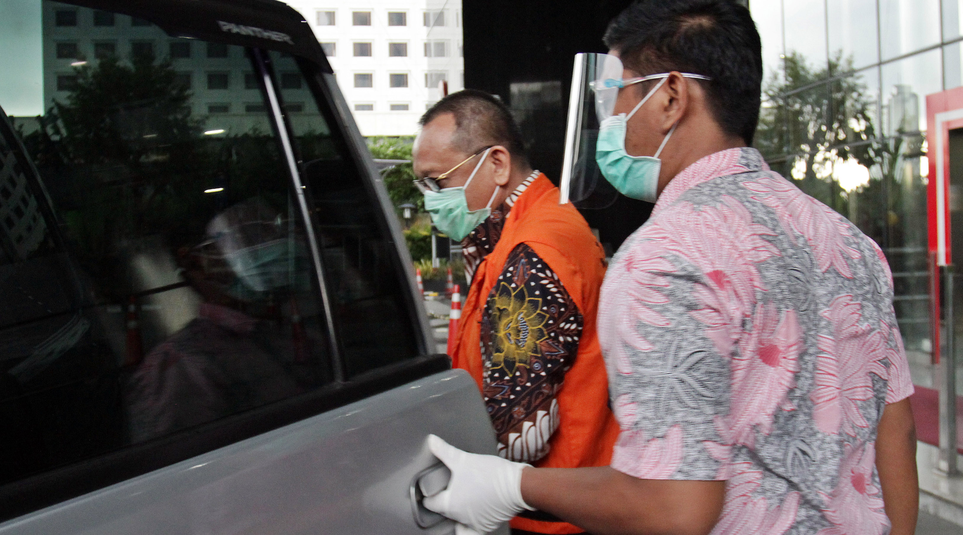 Nurhadi memakai rompi oranye memasuki mobil tahanan.