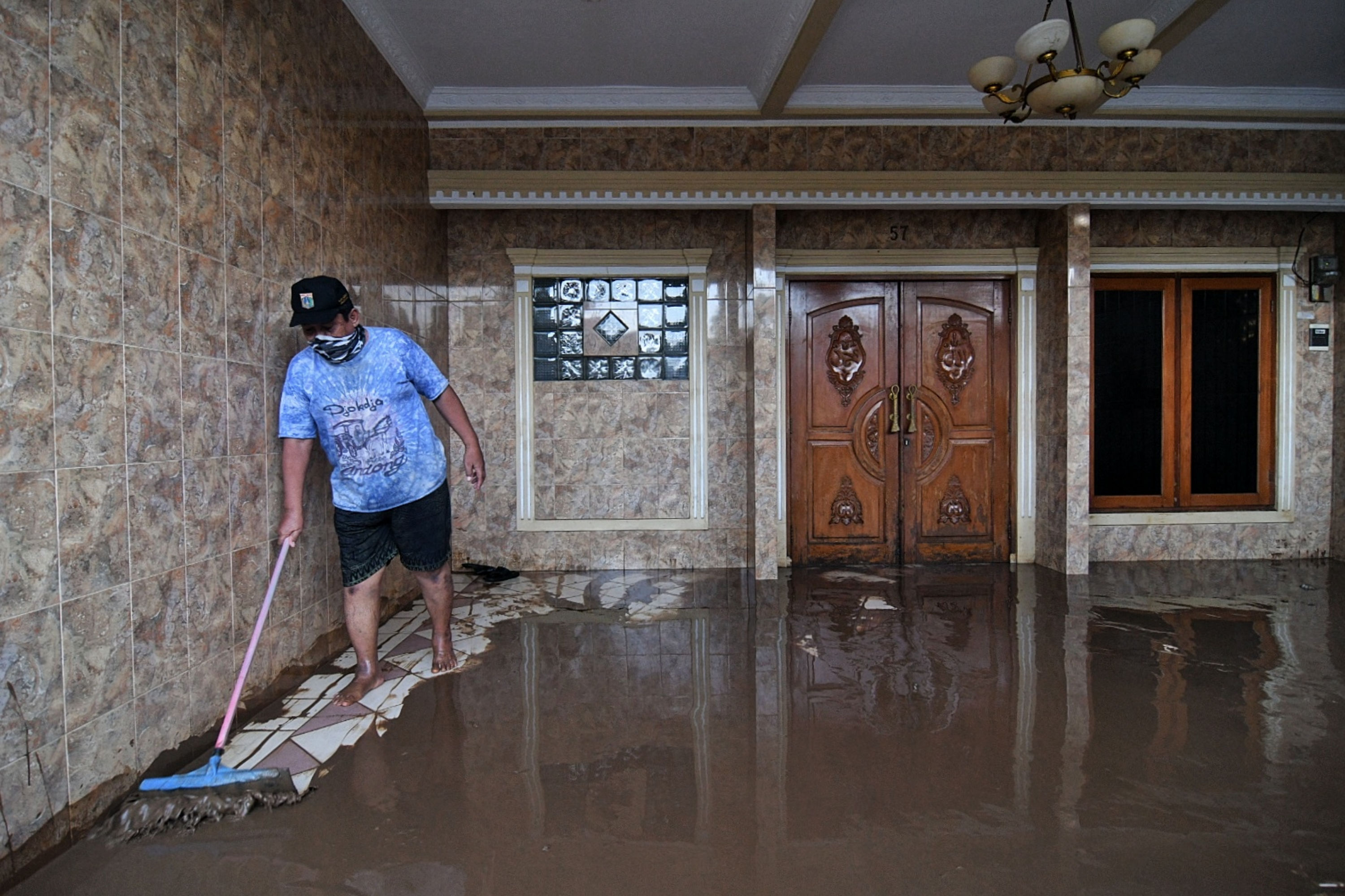 Warga membersihkan rumahnya saat banjir mulai surut di kawasan rw.08 Kelurahan Cawang, Jakarta Timur.