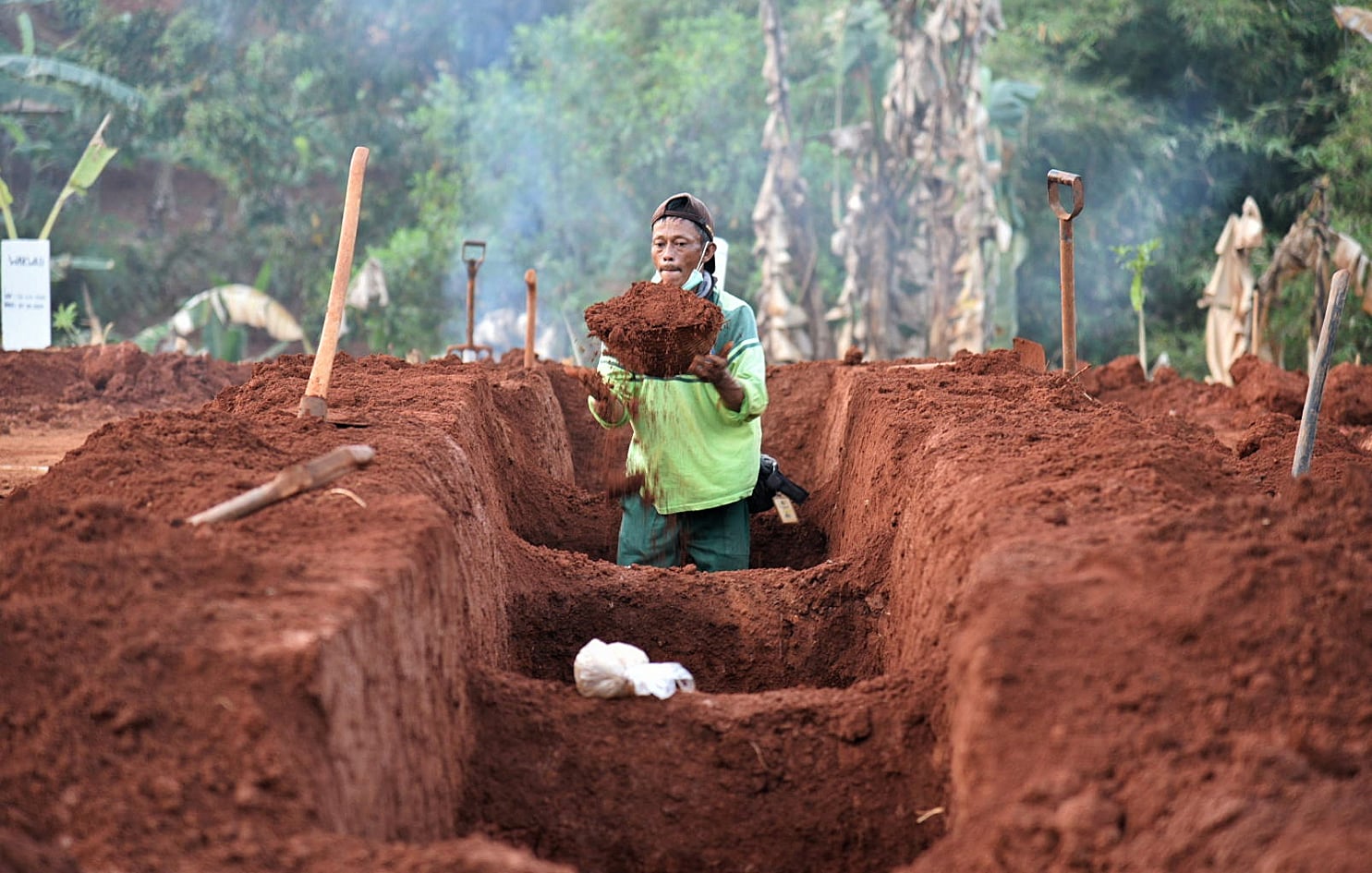 Seorang tukang penggali kubur mempersiapkan tempat pemakaman pasien covid-19 