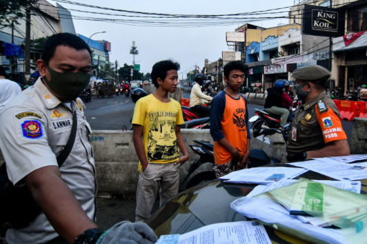 Petugas melakukan penindakan kepada pengendara yang tak menggunakan masker di Jalan Ragunan, Pasar Minggu, Jakarta Selatan, Jumat (24/7).