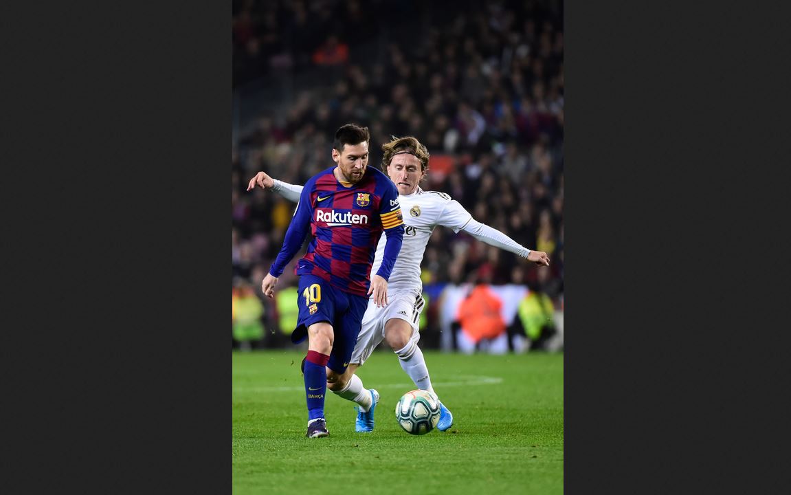 Lionel Messi (kiri) bertarung dengan Luca Modric 