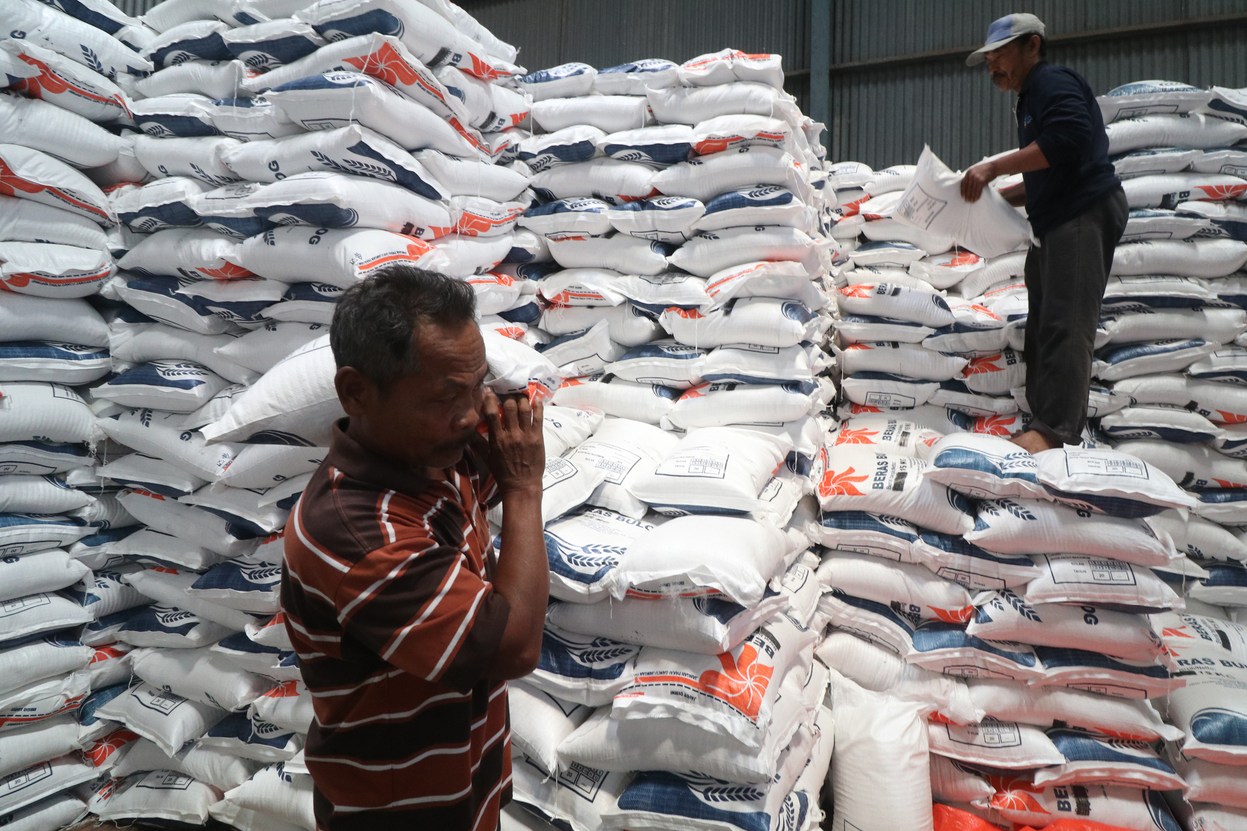 Pekerja menata beras bantuan sosial (bansos) sebelum didistribusikan ke masyarakat di gudang Bulog.