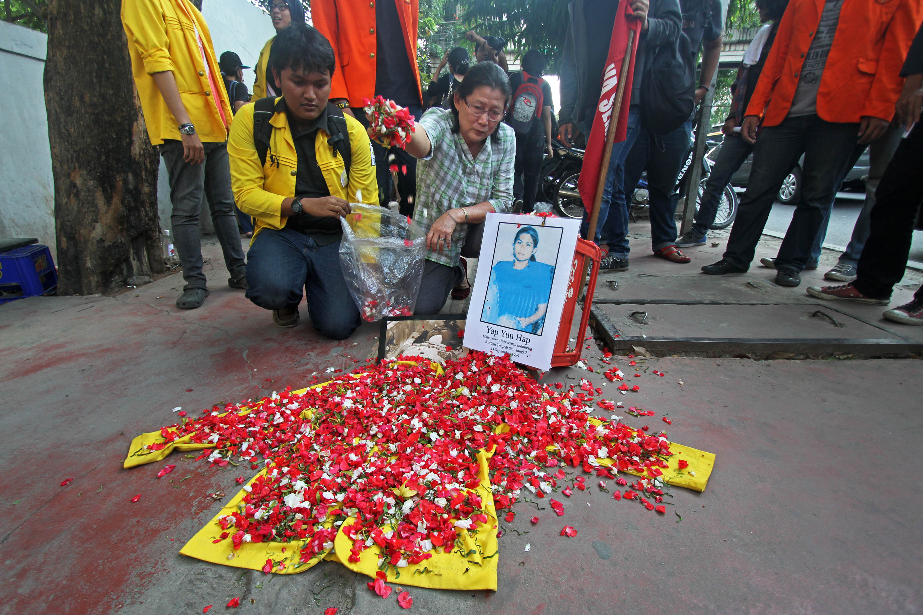 Ibu Yap Yun Hap, Ho Kim Ngo, menaburkan bunga di atas jaket alamamater dan foto anaknya di depan Kampus Unika Atma Jaya, Jakarta.