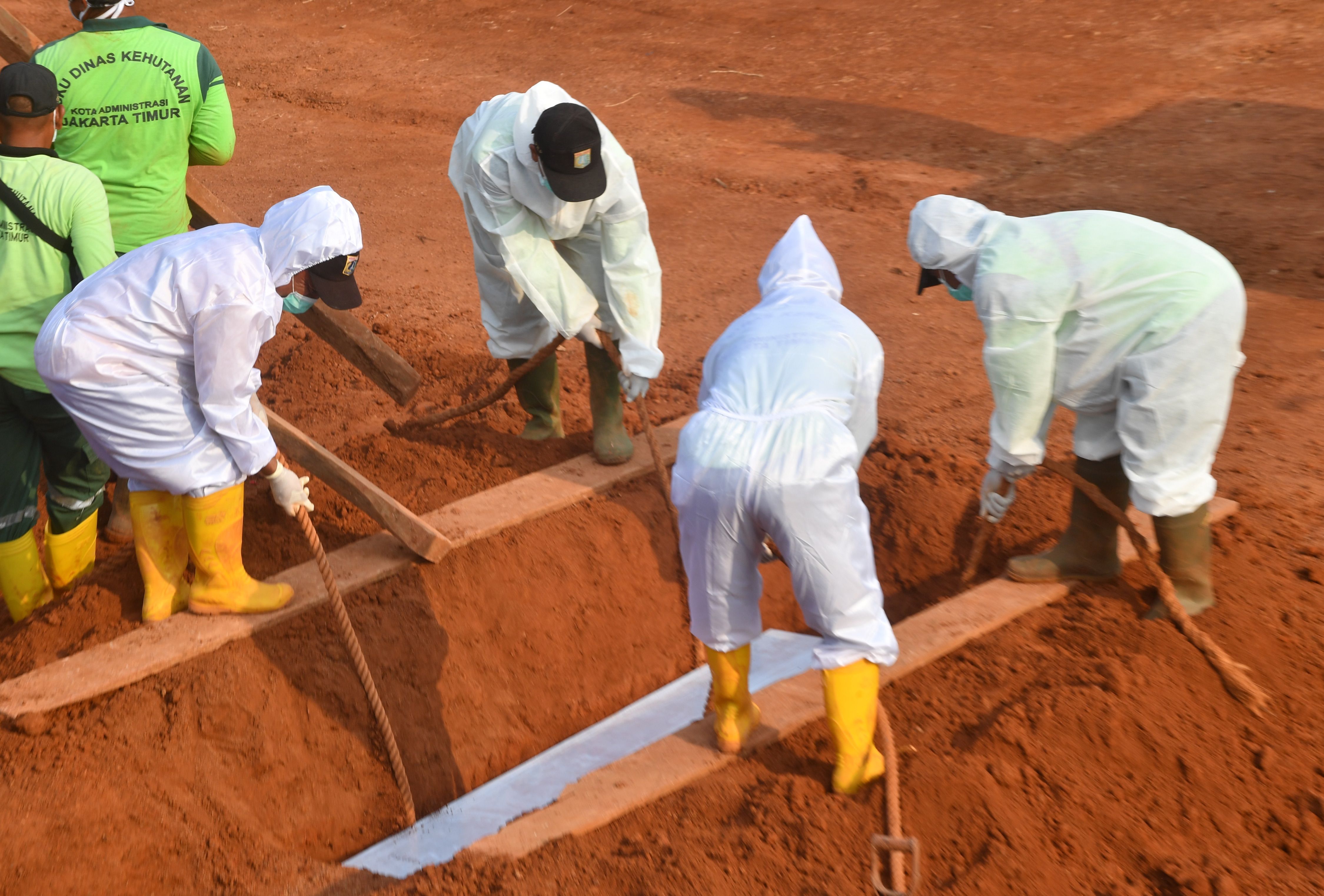 Petugas menurunkan peti jenazah pasien covid-19 di TPU Pondok Ranggon, Jakarta.