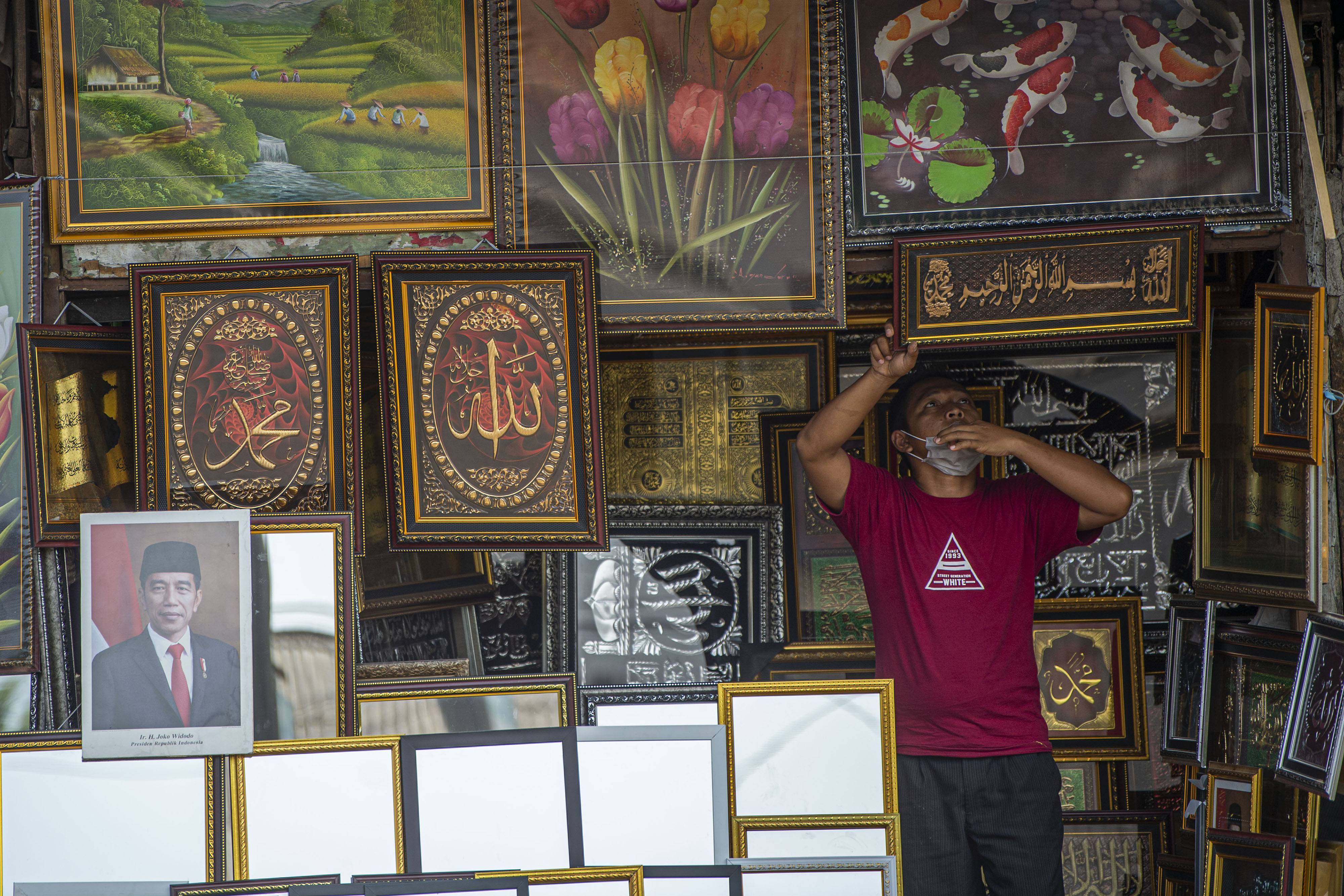 Pedagang menata kerajinan pigura dan kaligrafi di kawasan Pasar Minggu, Jakarta.