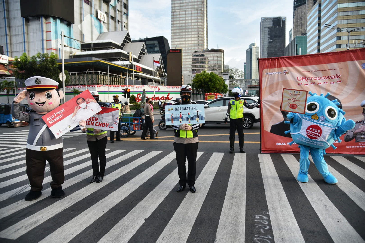 Petugas yang menggunakan kostum berbentuk virus korona membawa poster mengenai sosialisasi penggunaan masker di kawasan Sarinah, Jakarta.