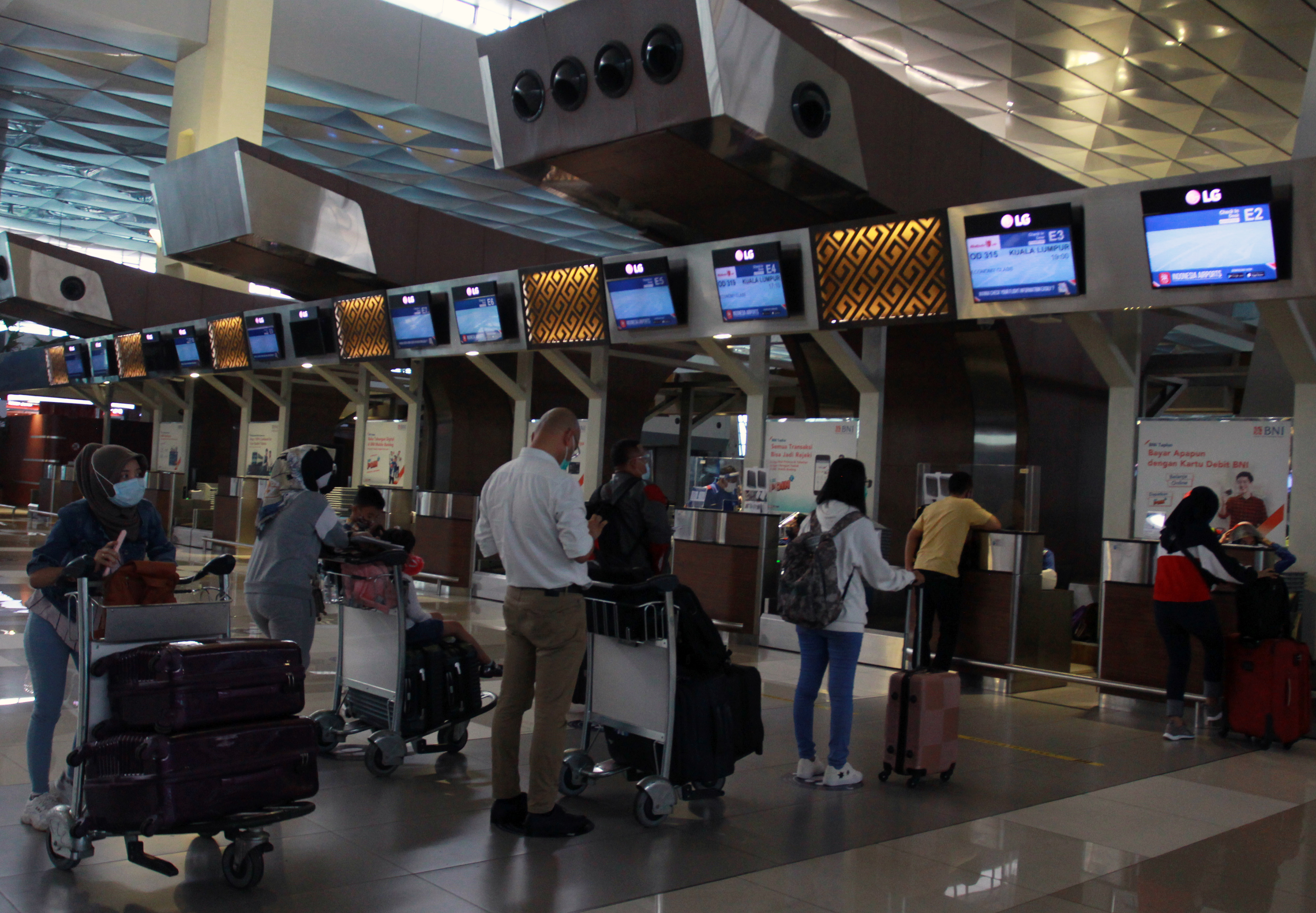 Calon penumpang dengan menerapkan jaga jarak mengantre untuk lapor diri di Terminal 3 Bandara Soekarno-Hatta, Tangerang, Banten.