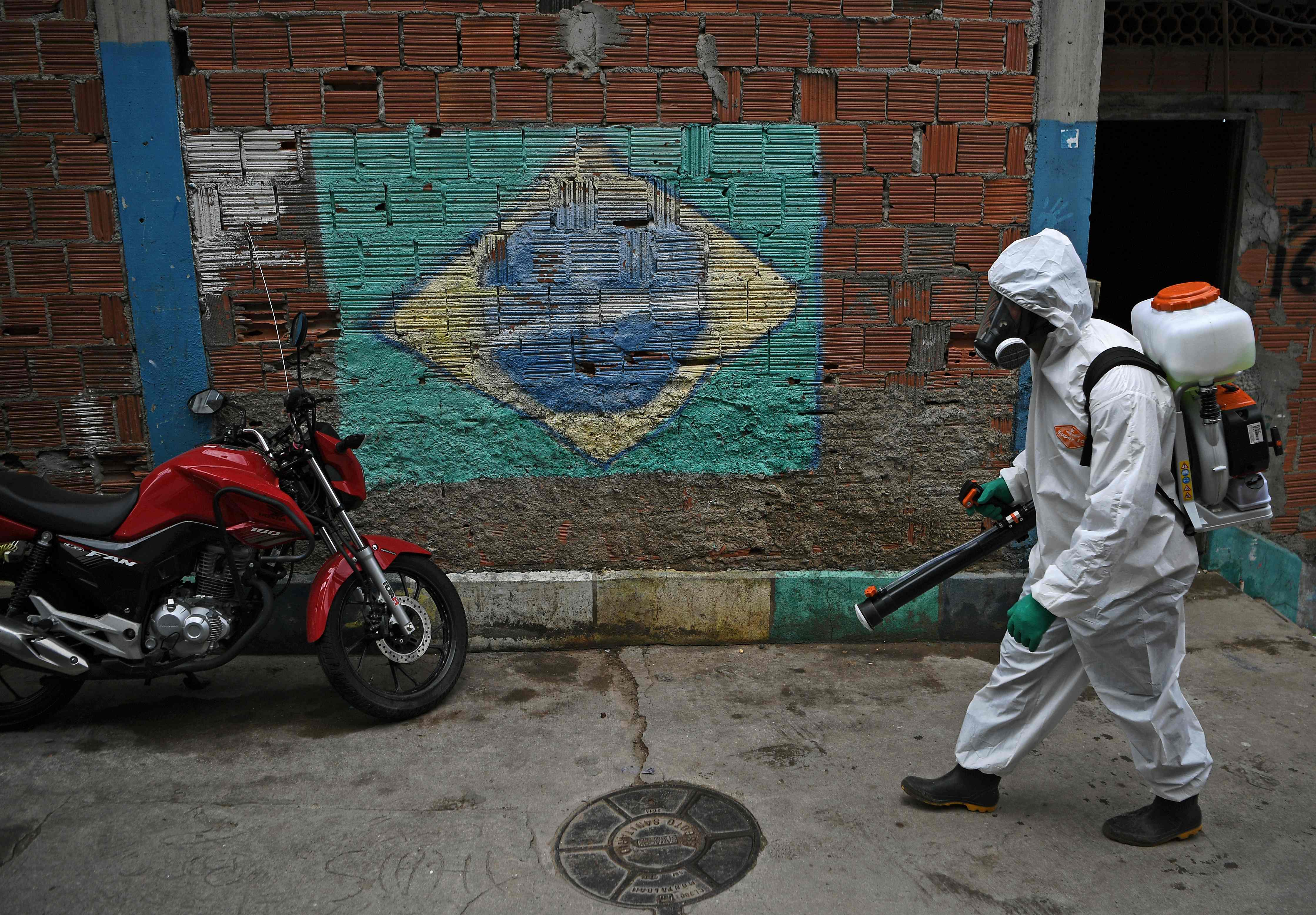 Petugas memakai APD sedang menyemprot disinfektan di Babilonia favela,  Rio de Janeiro, Brazi
