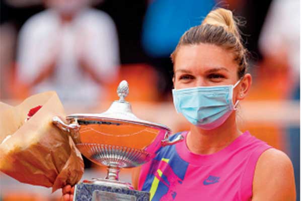 Petenis Rumania Simona Halep mengenakan masker saat berpose dengan trofi setelah menjuarai Italia Terbuka 2020.