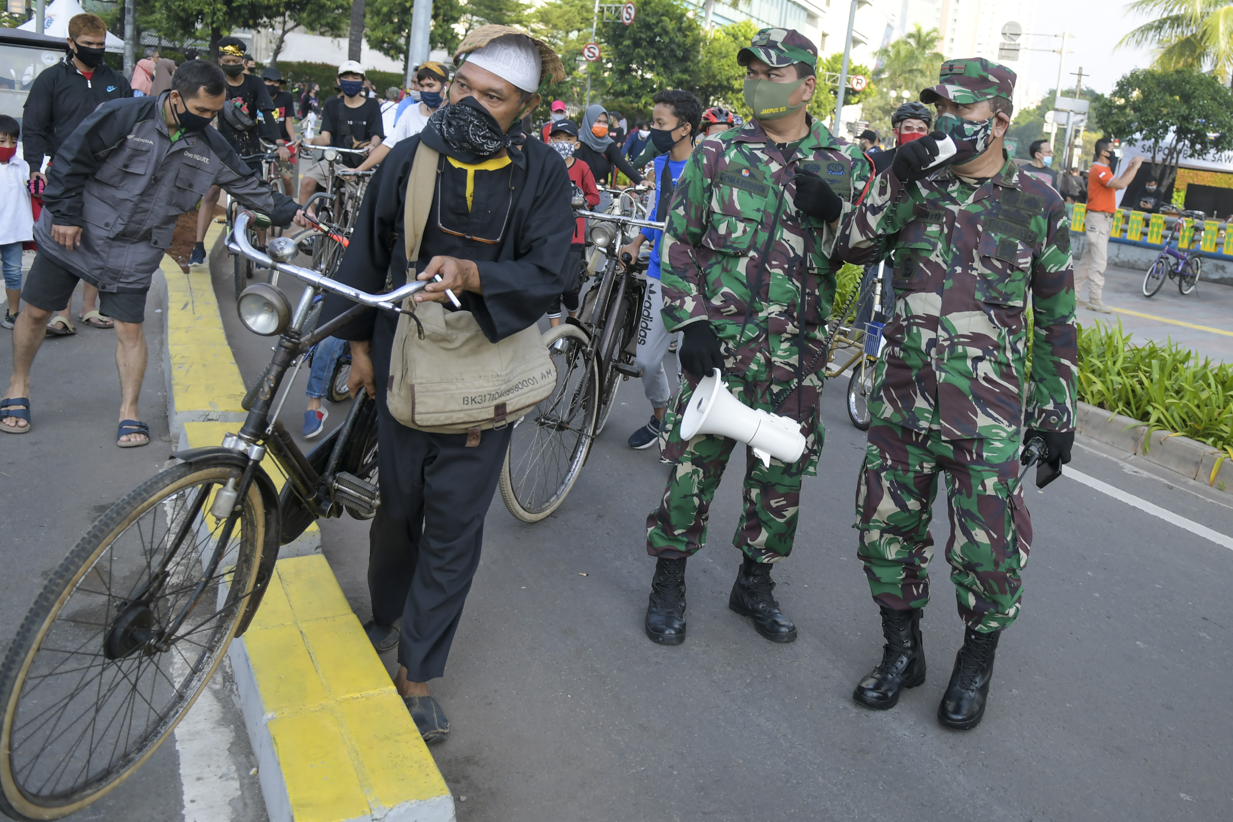 Petugas TNI menghimbau warga untuk menerapkan protokol kesehatan saat berolahraga pada Hari Bebas Kendaraan Bermotor (HBKB) .