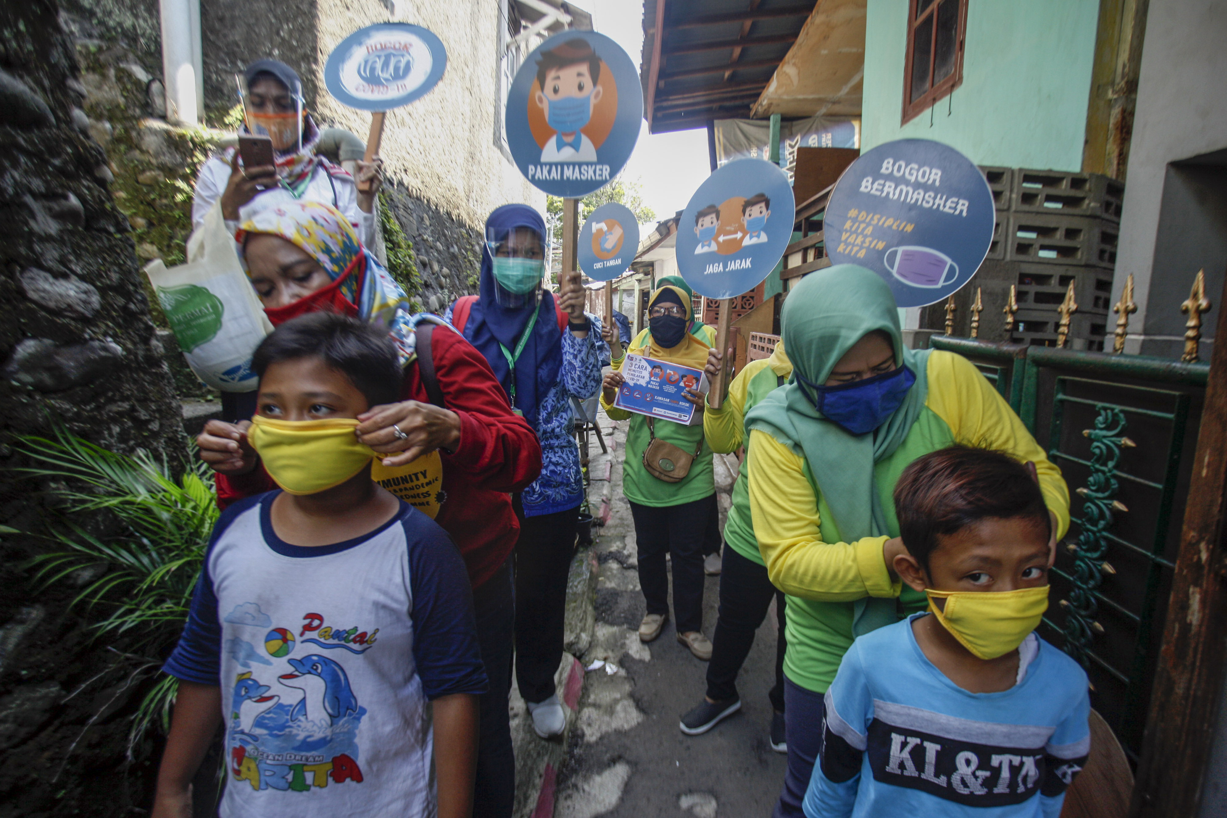 Petugas Puskesmas memakaikan masker kepada seorang anak saat sosialisasi gerakan 3M di pemukiman warga Tanah Sareal, Kota Bogor, Jabar.
