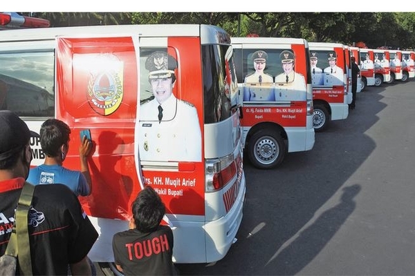 Ilustrasi -- Pekerja menutup foto petahana calon Bupati Jember, Faida, di mobil ambulans desa di Kantor Pemkab Jember, Jawa Timur, kemarin.