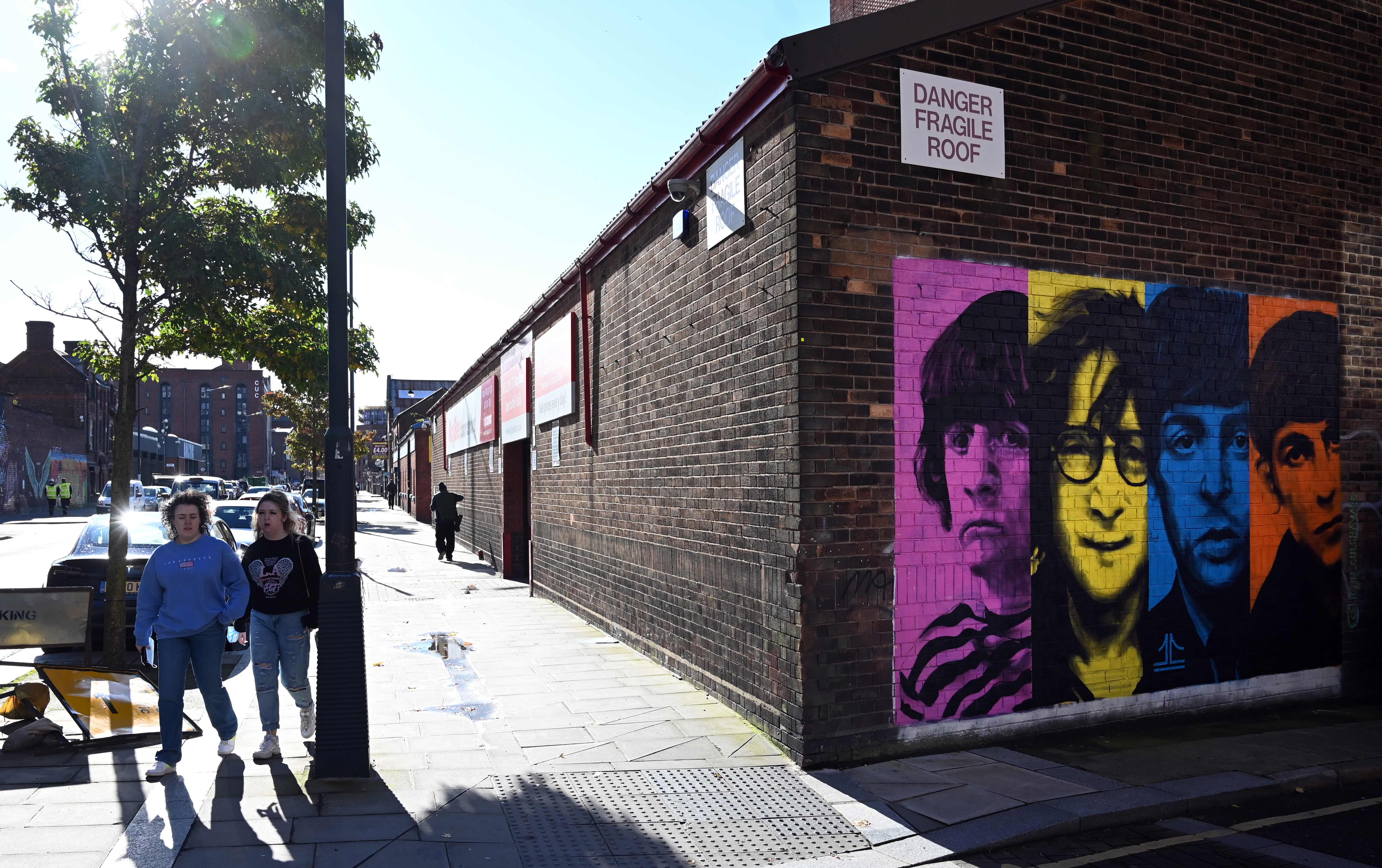 Warga Liverpool, Inggris, melintasi mural band legendaris The Beatles.