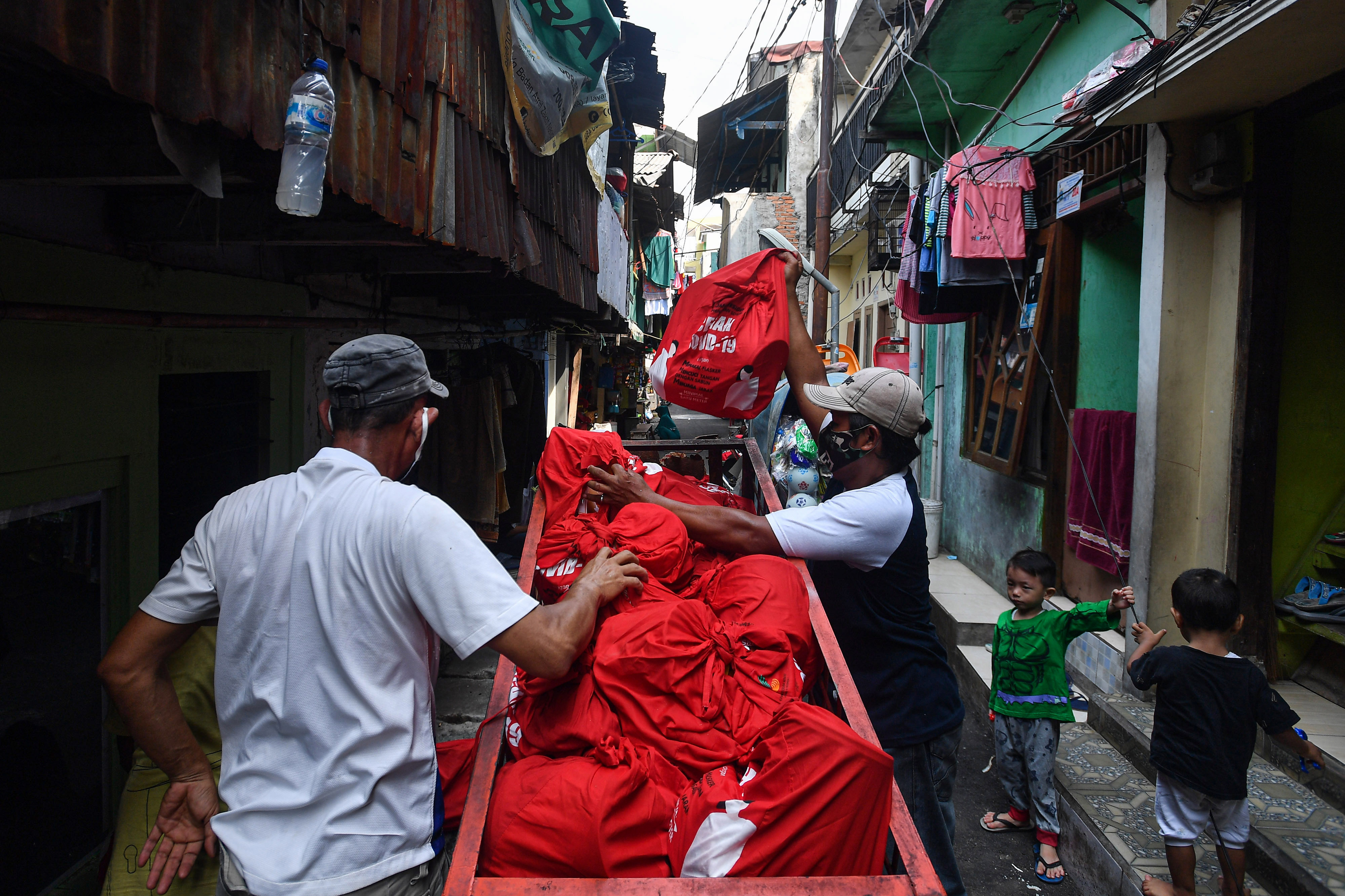 Warga menurunkan paket bantuan sembako Presiden saat didistribusikan di kawasan permukiman Bendungan Hilir, Tanah Abang,