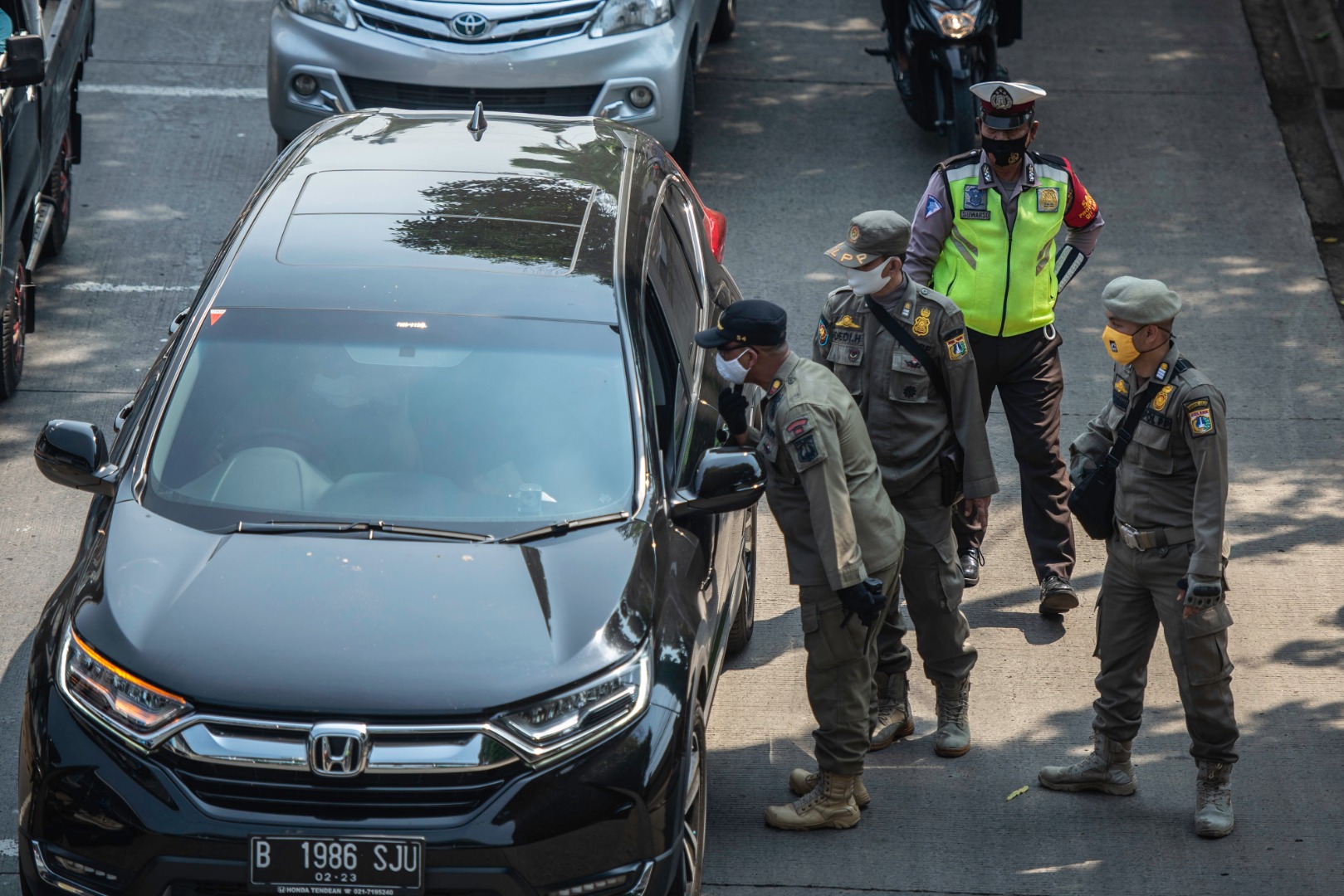 Petugas menghentikan sopir mobil tidak bermasker dalam Operasi Yustisi Protokol Covid-19 di kawasan Jati Padang, Jakarta.