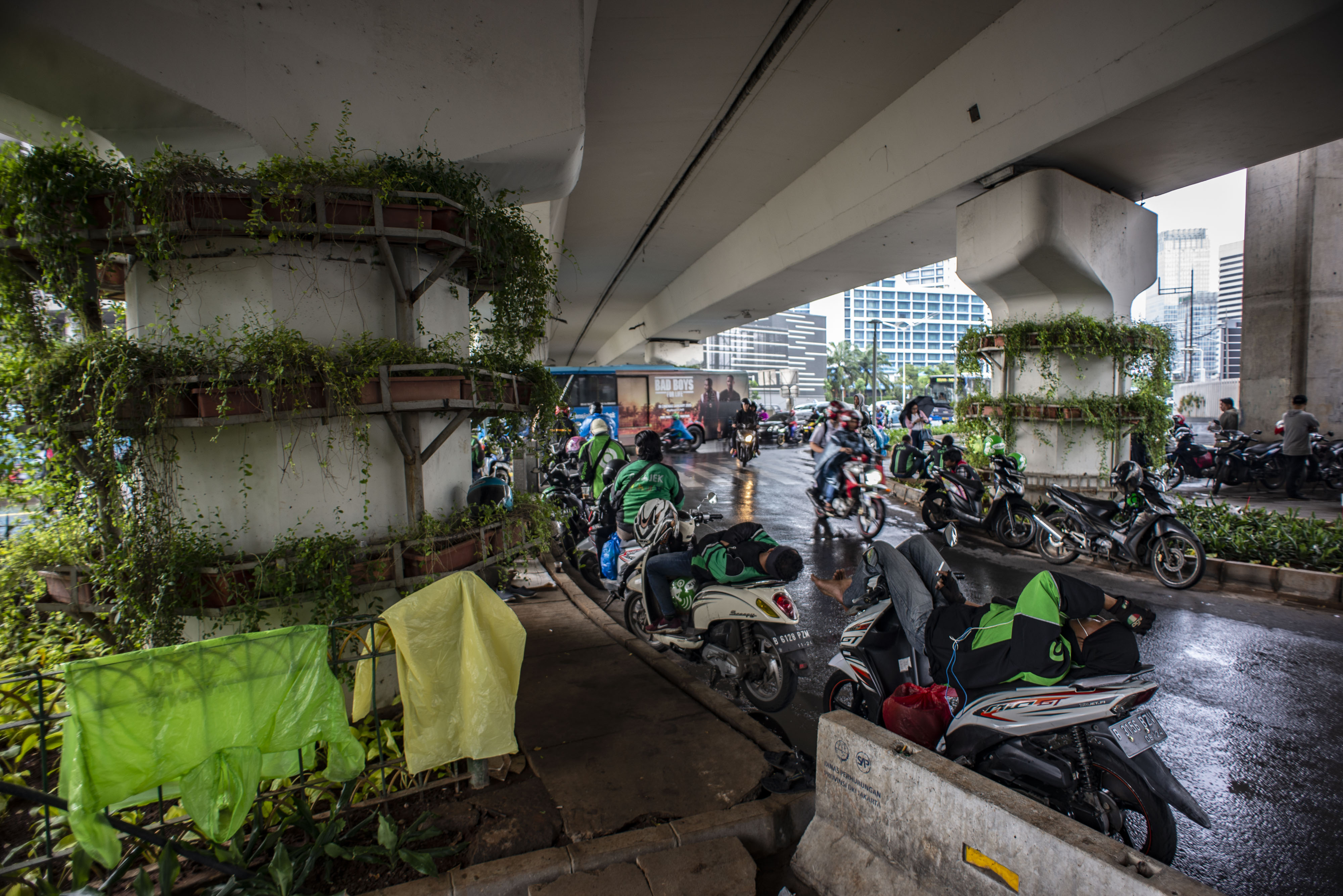 Pengendara sepeda motor berteduh di bawah Flyover