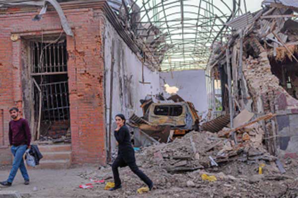 Penduduk lokal berjalan di dekat bangunan yang hancur terkena rudal di Ganja, Azerbaijan, kemarin