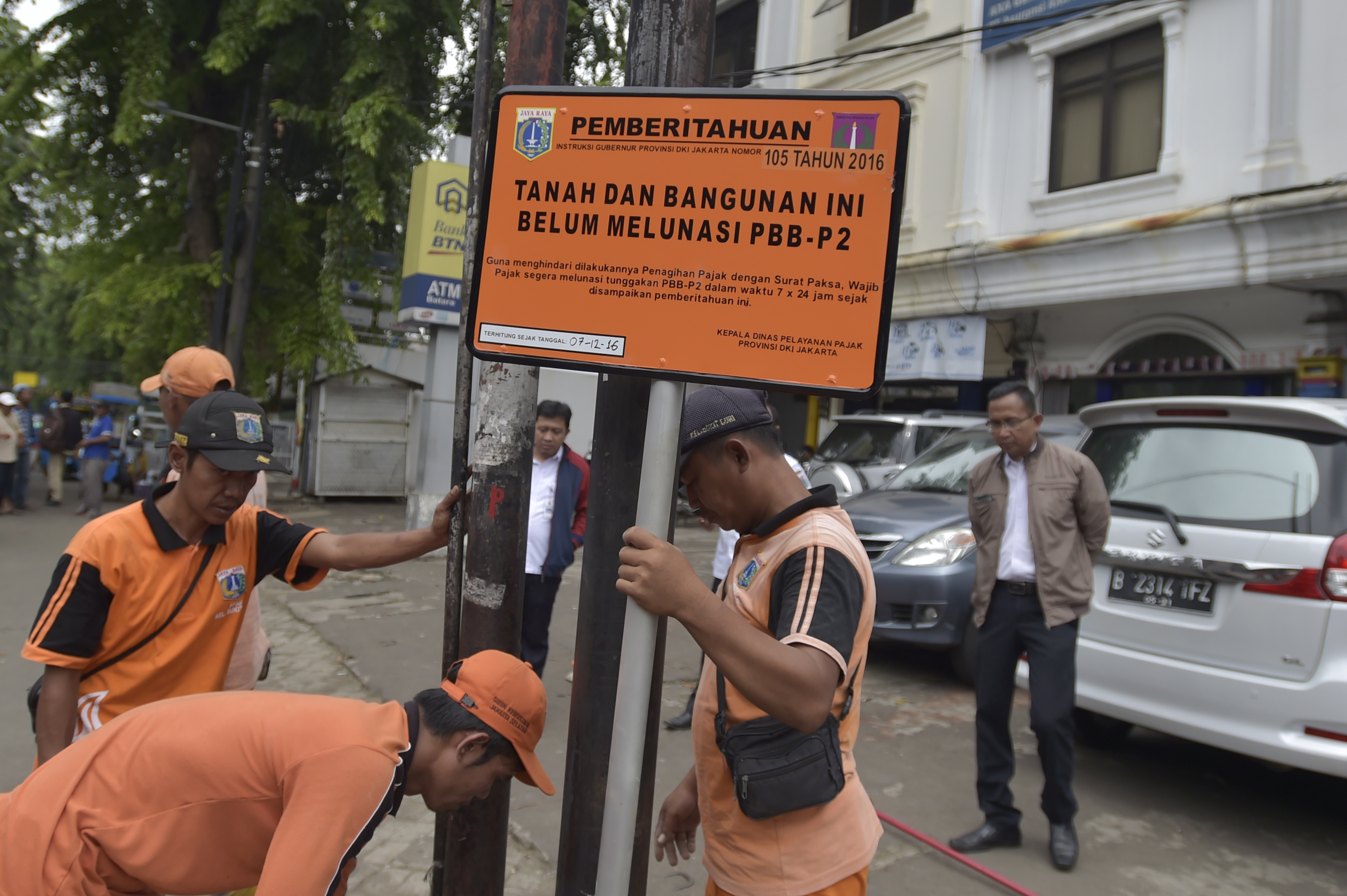 Petugas memasang plang piutang PBB-P2 di salah satu bangunan di kawasan Kampung Melayu, Jakarta, Rabu (7/12)