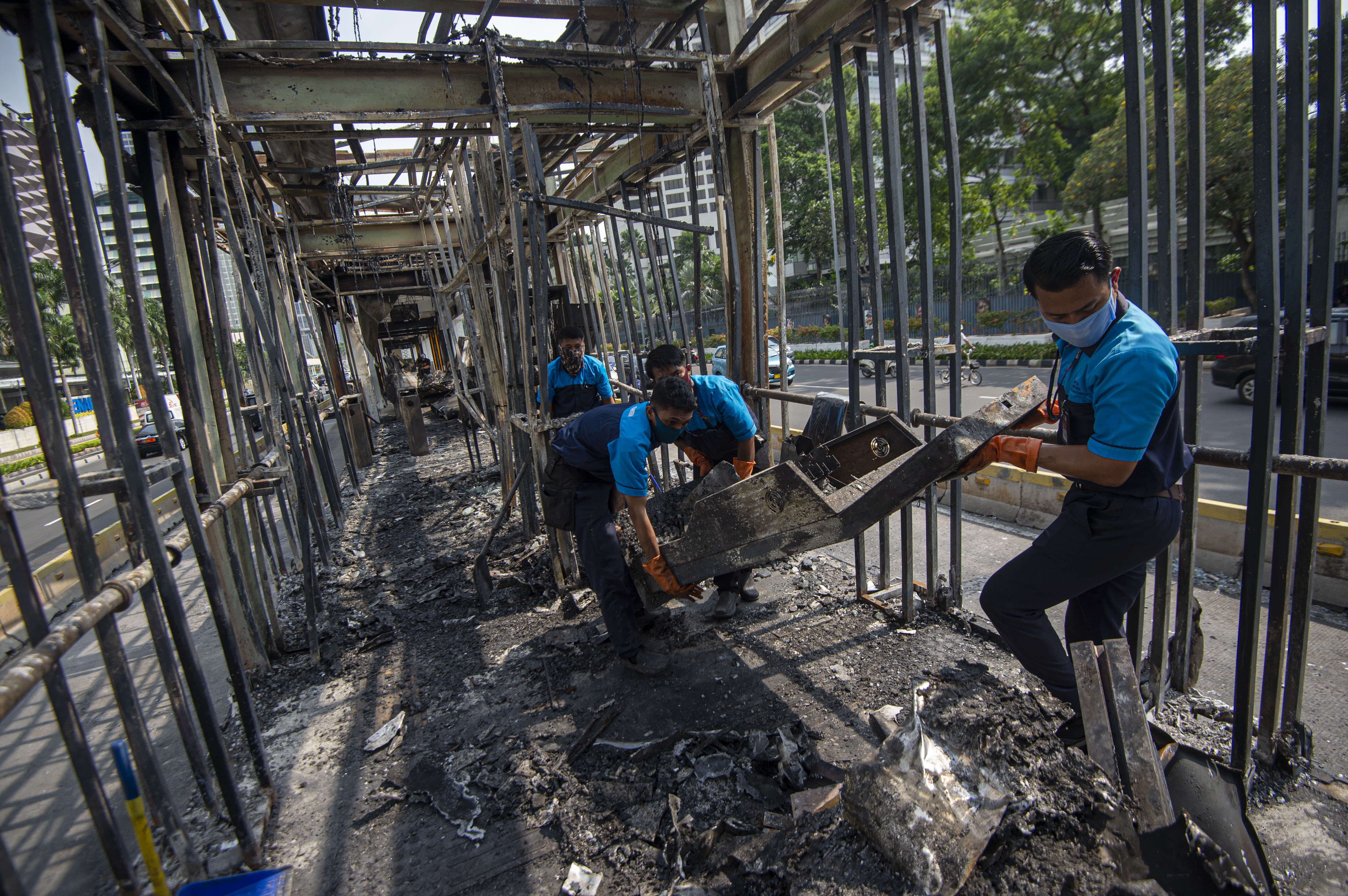 Petugas membersihkan puing Halte Bus Trans-Jakarta Tosari yang hangus saat kericuhan unjuk rasa, Jumat (9/10).
