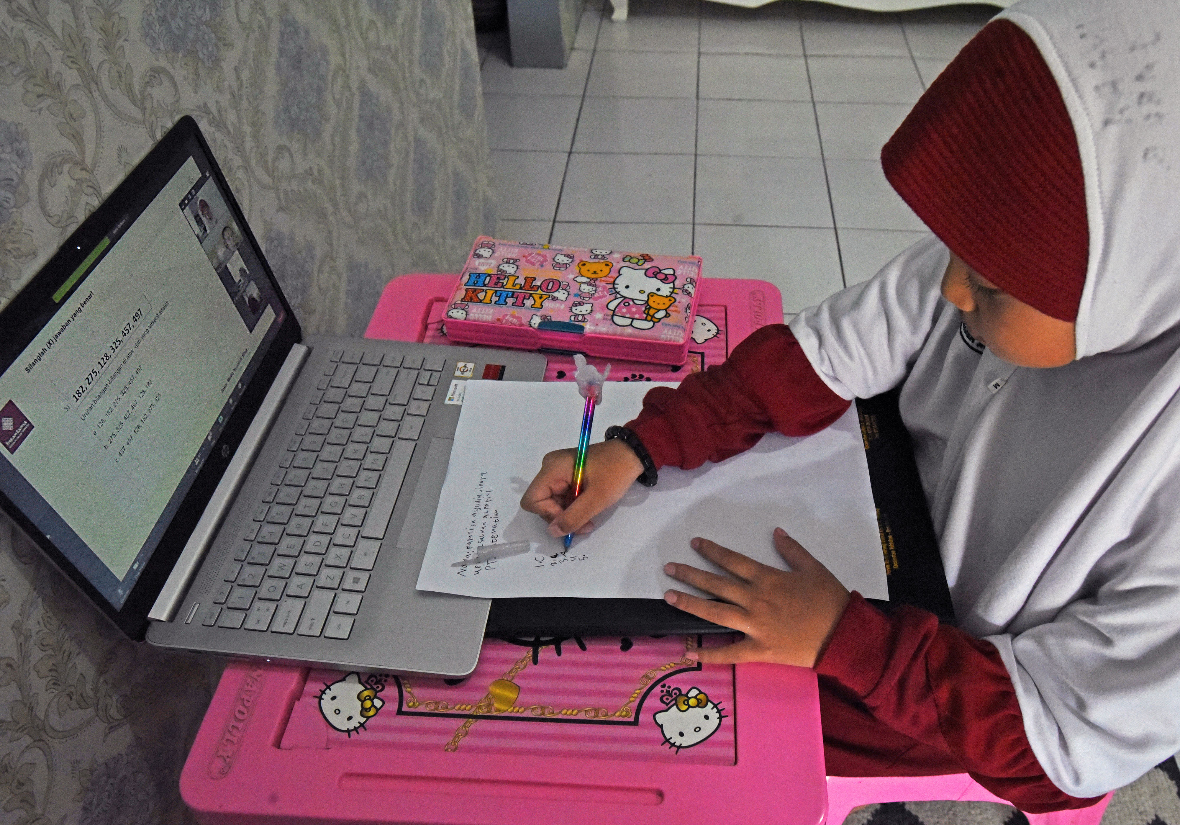Seorang murid SD tengah mengerjakan latihan soal saat mengikuti pembelajaran jarak jauh secara daring di rumahnya. 