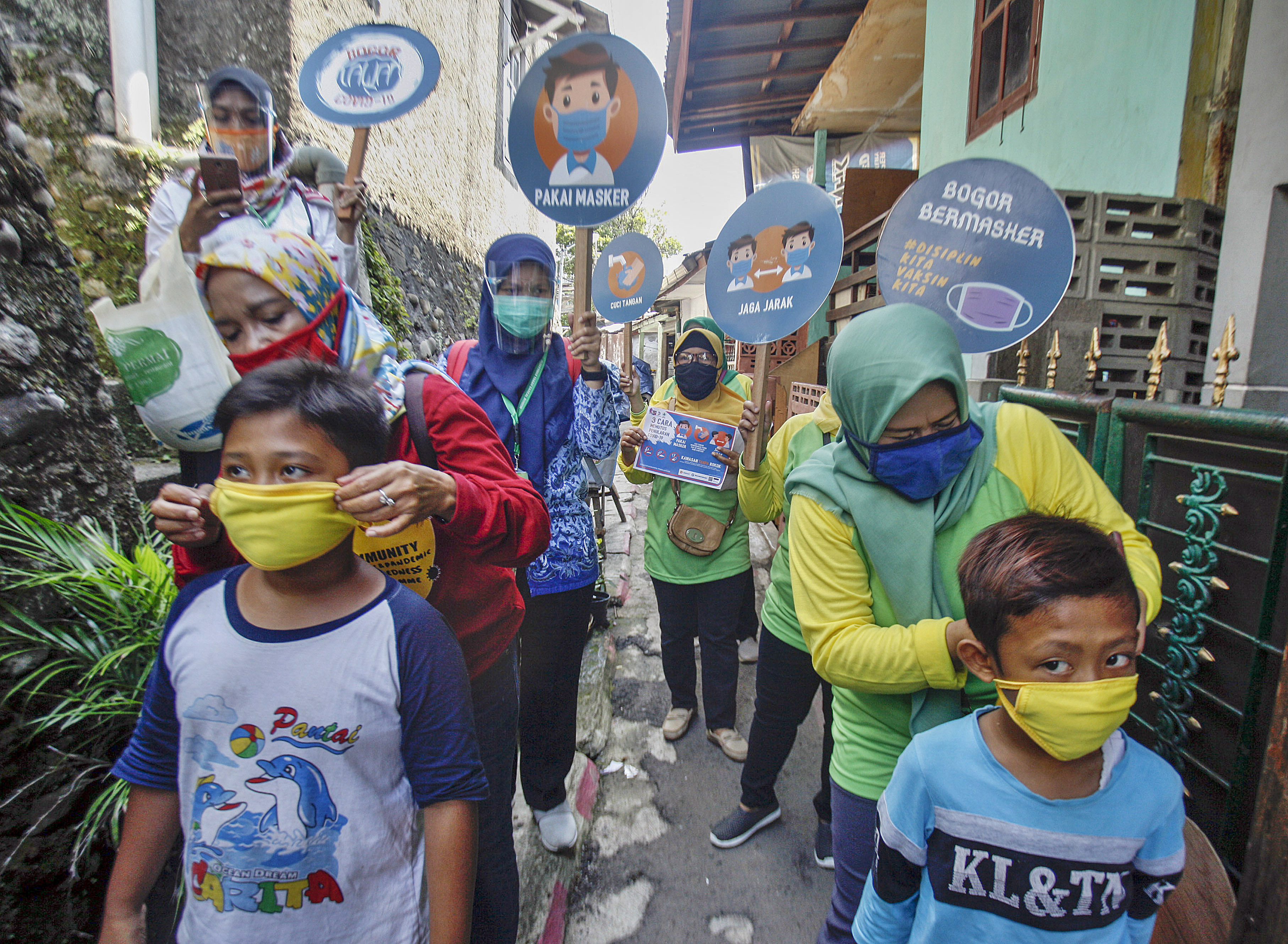 Petugas puskesmas memakaikan masker kepada anak-anak di Bogor, Jawa Barat.