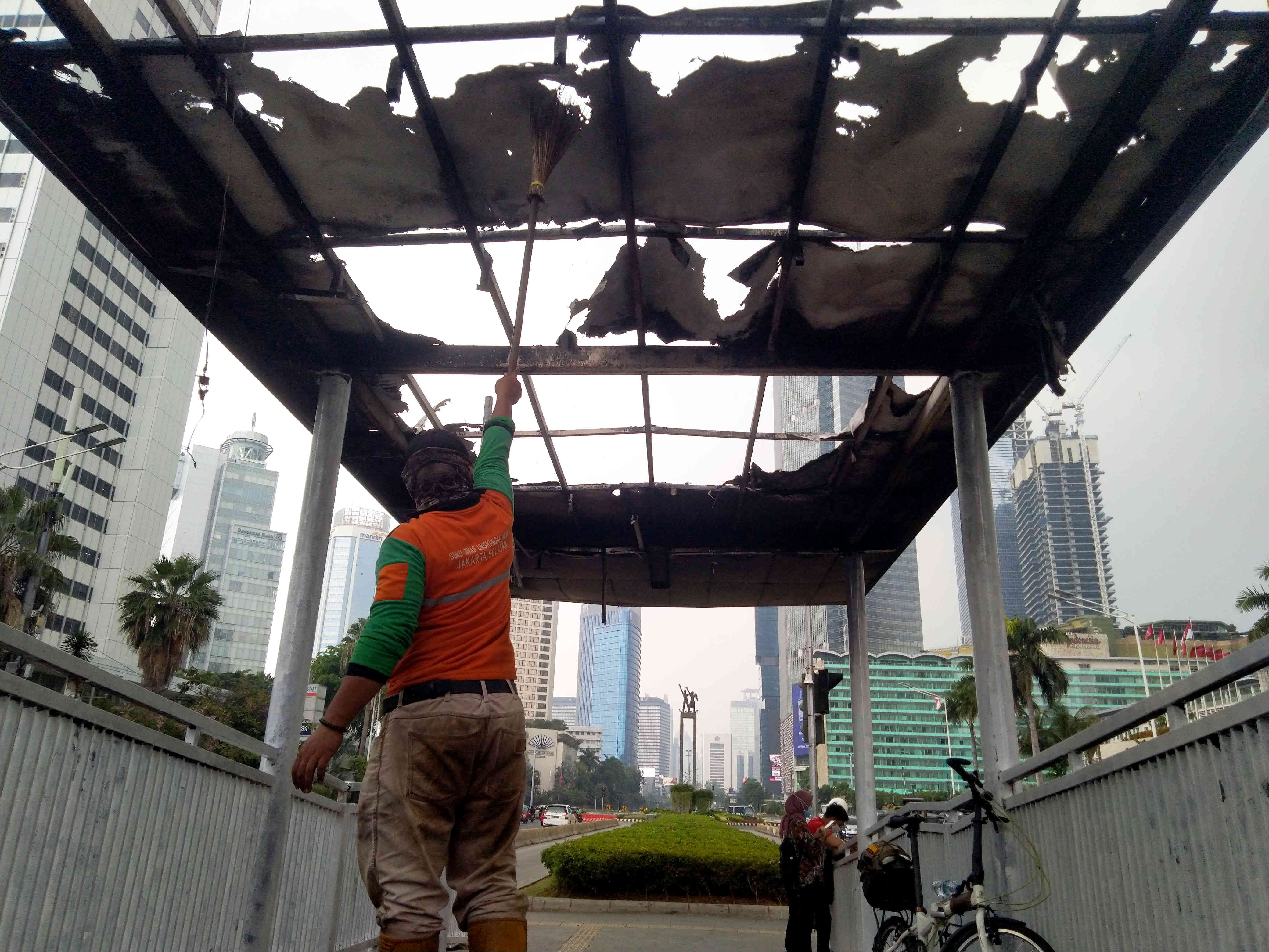 Petugas membersihkan puing Halte Trans-Jakarta Tosari yang dibakar saat kericuhan unjuk rasa menolak pengesahan Undang-Undang Cipta Kerja.