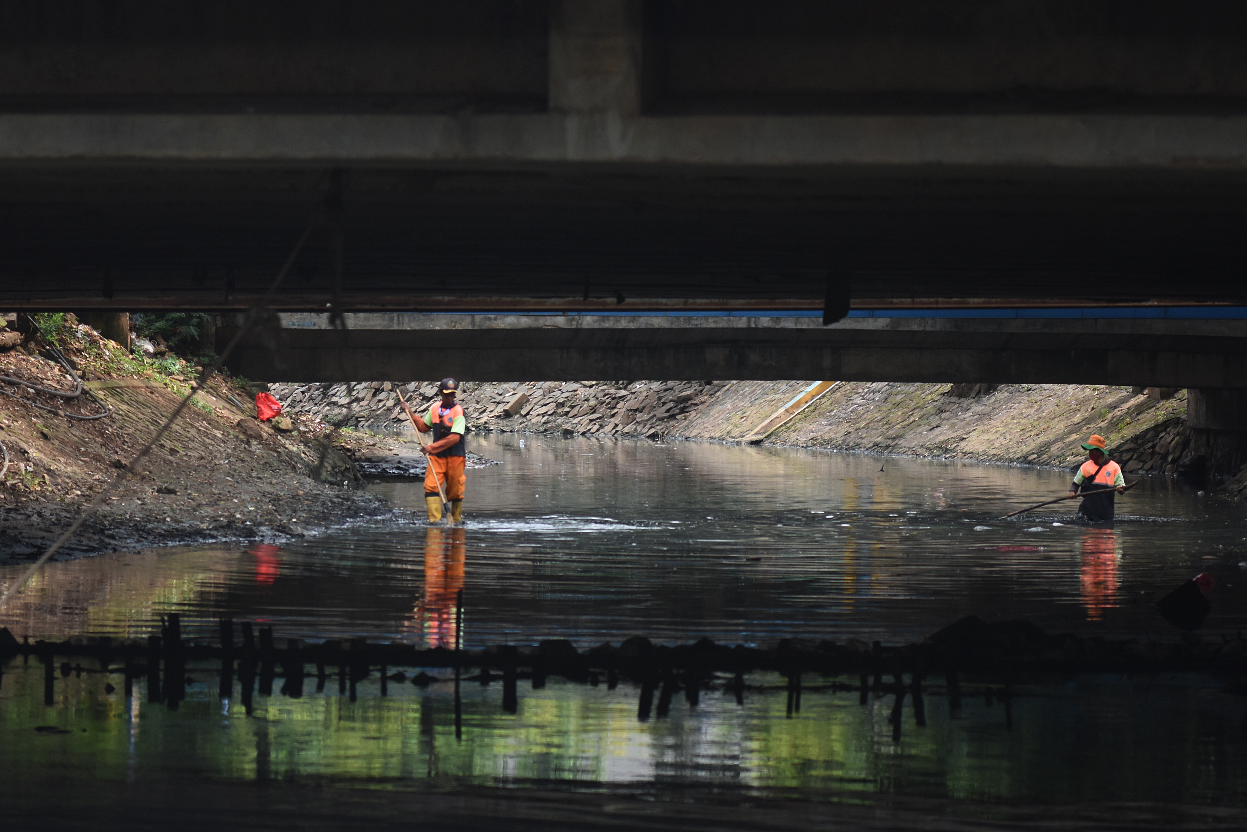 Petugas UPK Badan Air Dinas Lingkungan Hidup Jakarta Selatan membersihkan sampah yang berada di aliran Kali Cideng di Jakarta.