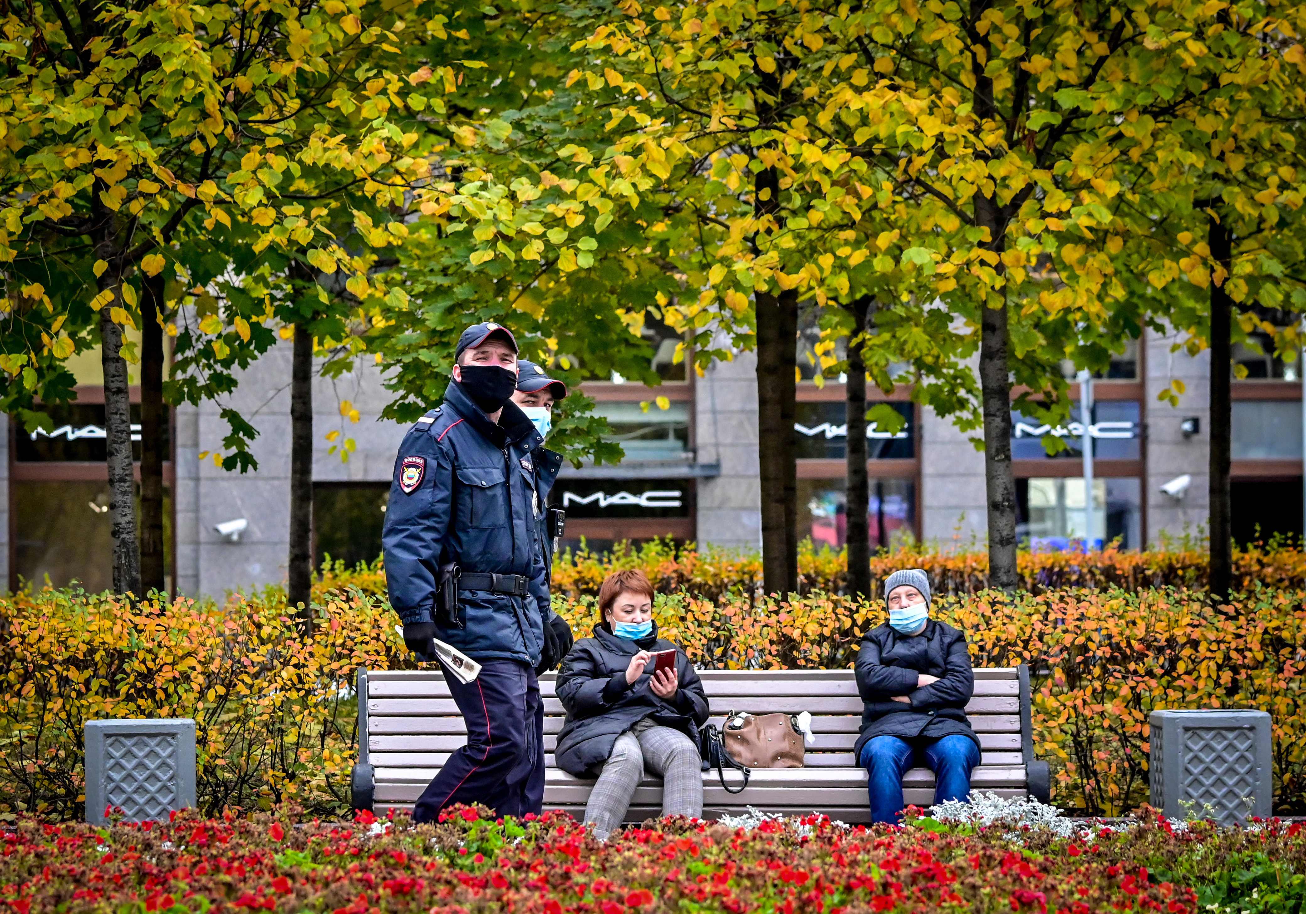 Dua polisi memakai masker melintas di taman pusat Kota Moskow. Rusia mempersiapkan vaksin covid-19 saat rumah sakit mulai kekurangan dokter.