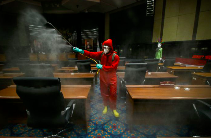 Petugas menyemprotkan cairan disinfektan di ruang sidang paripurna DPRD DKI Jakarta, Rabu (29/7/2020)  