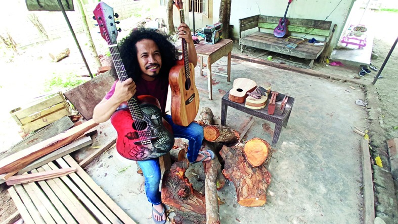 Musikus yang juga merupakan korban likuefaksi di daerah Balaroa, Kota Palu, Aci Karibo, berpose di antara gitar buatannya.