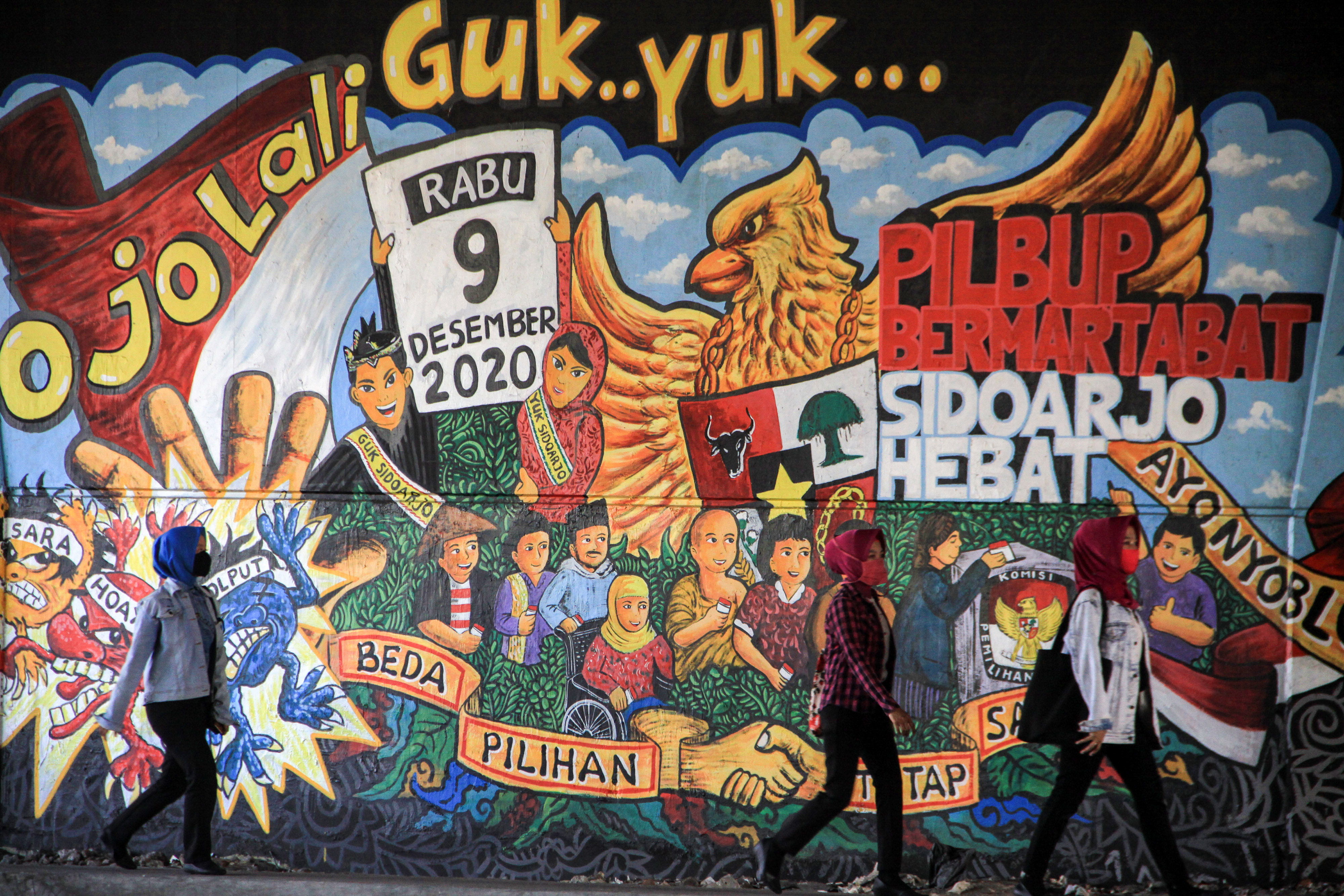 Warga melintasi mural terkait Pilkada 2020 di wilayah Sidoarjo, Jawa Timur.