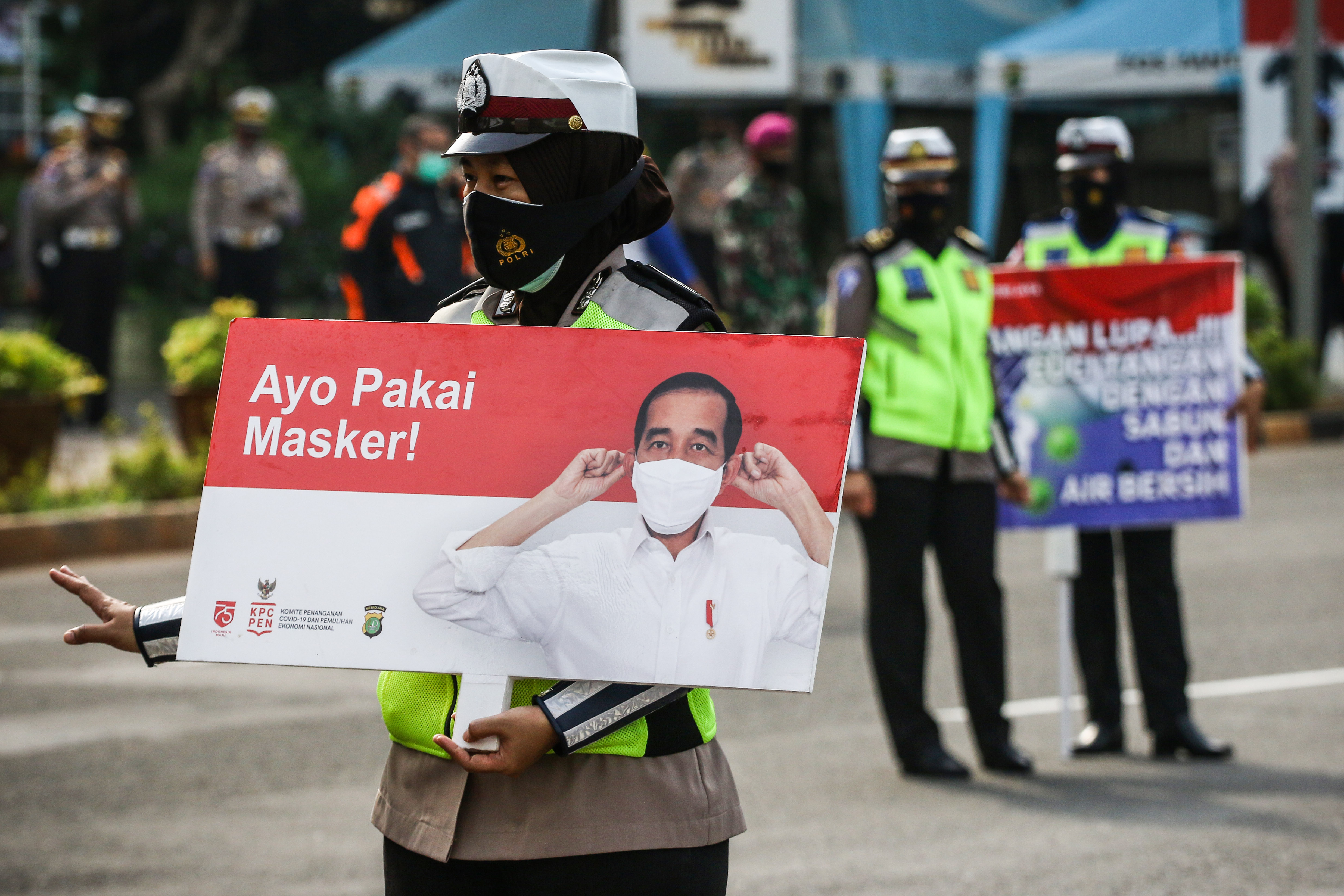 Petugas kepolisian melakukan sosialisasi protokol kesehatan di kawasan Bundaran HI, Jakarta.