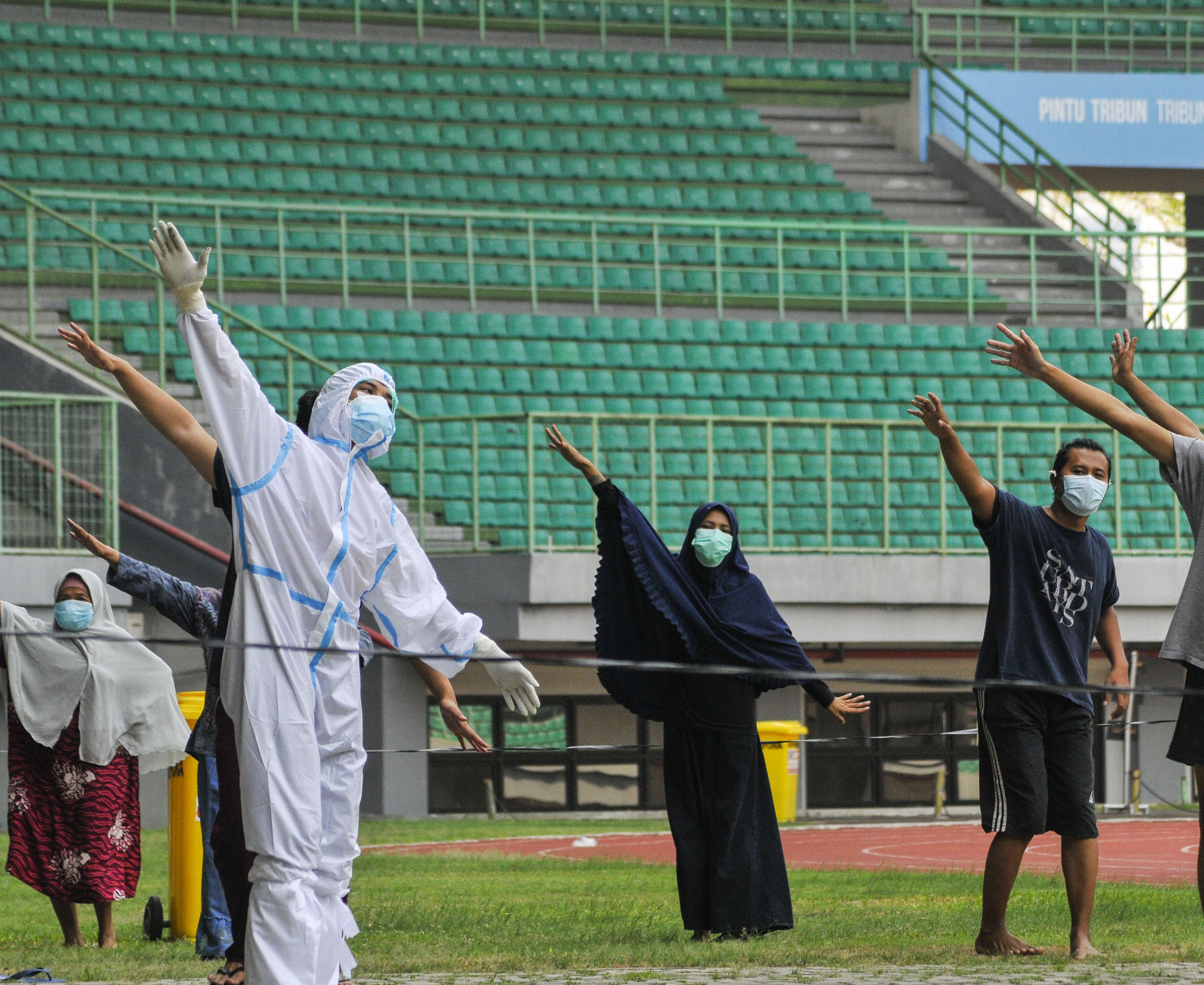 Petugas medis (kiri) memimpin senam pagi pasien covid-19 berstatus OTG di Stadion Patriot Chandrabhaga, Bekasi, Jawa Barat, Senin (28/9).