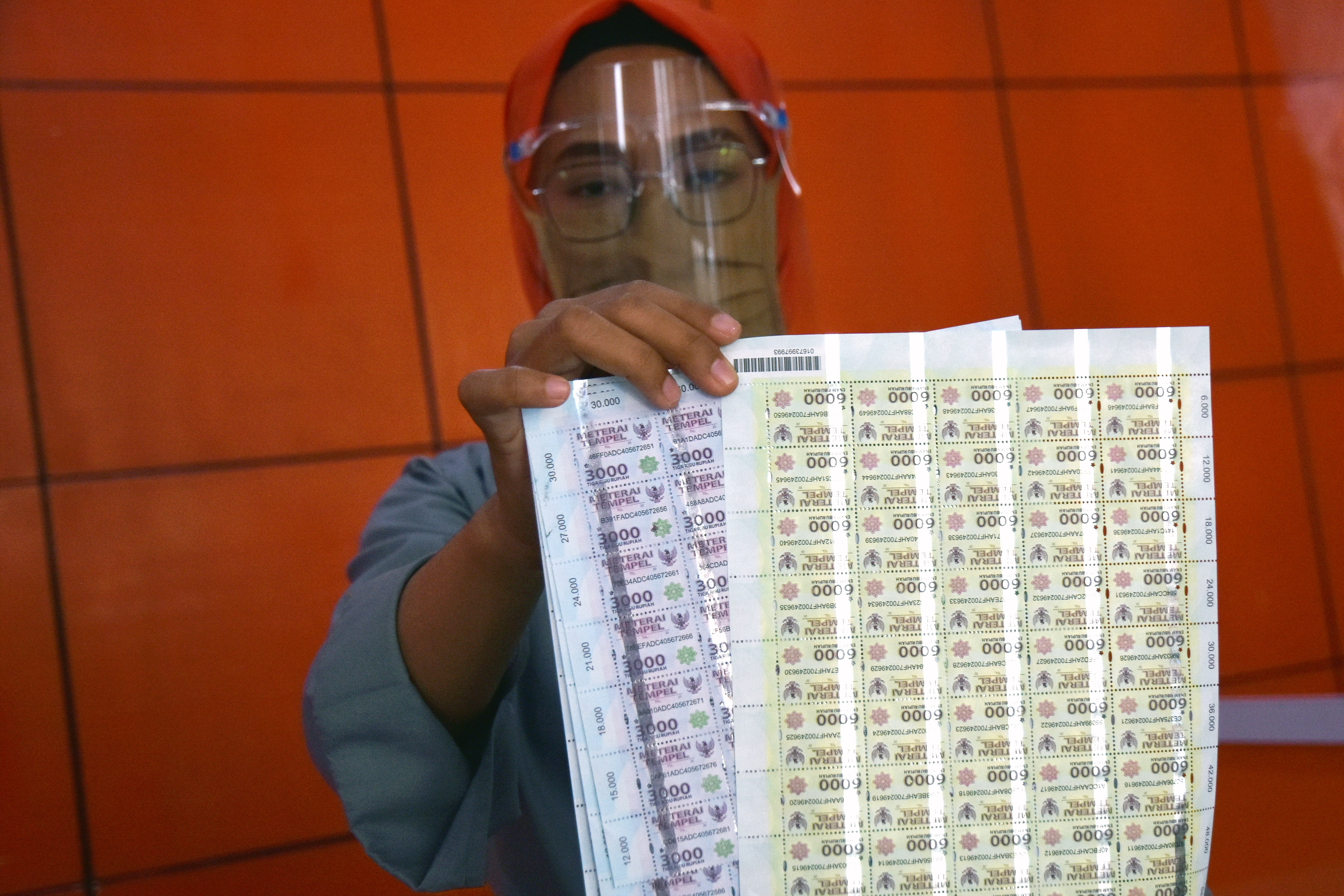 Seorang pegawai Kantor Pos menunjukkan lembaran materai Rp3.000 dan Rp6.000 di Kota Pekanbaru, kemarin.