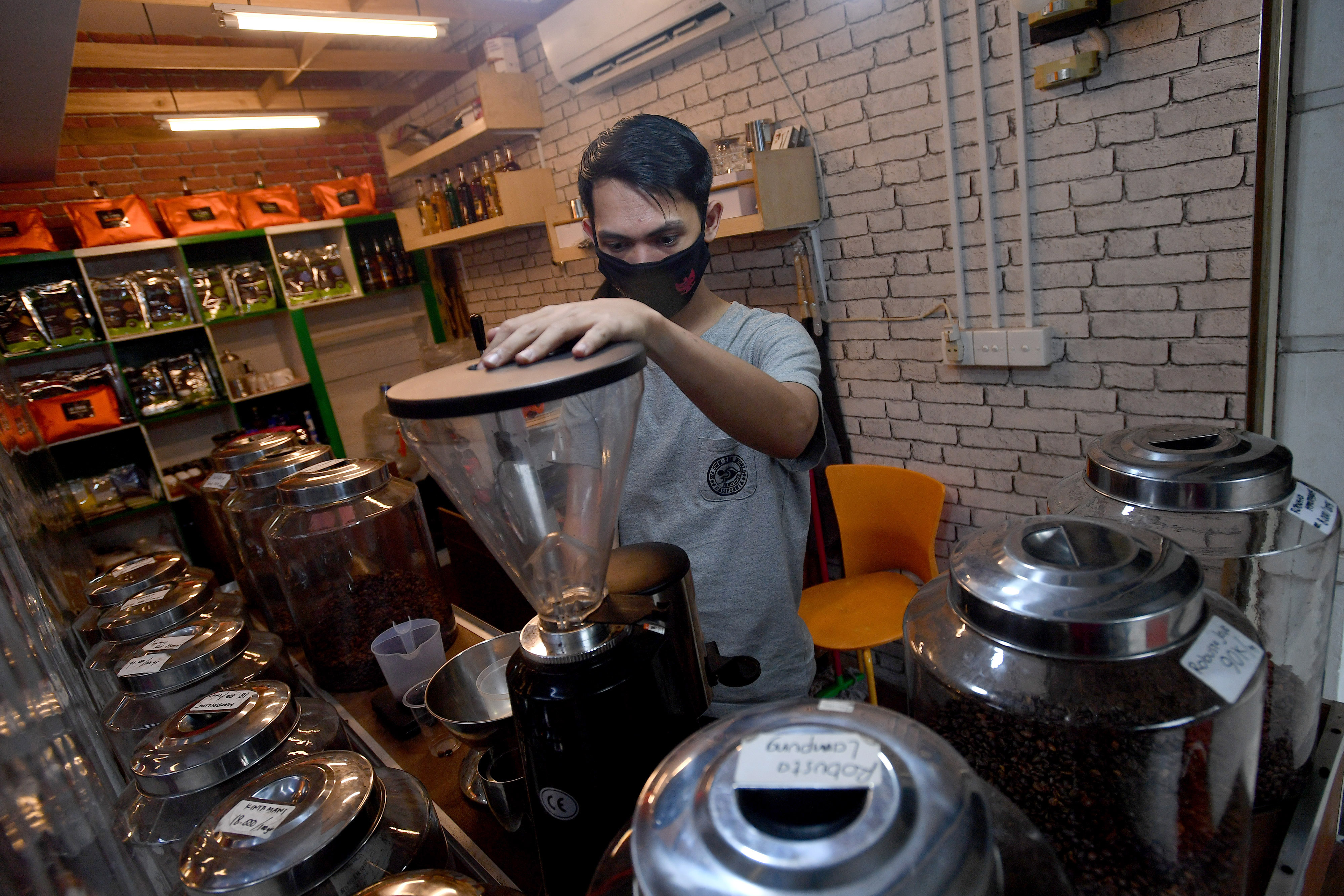 Seorang barista menggiling kopi di gerai Terminal Kopi Nusantara, Pasar Santa, Jakarta Selatan.