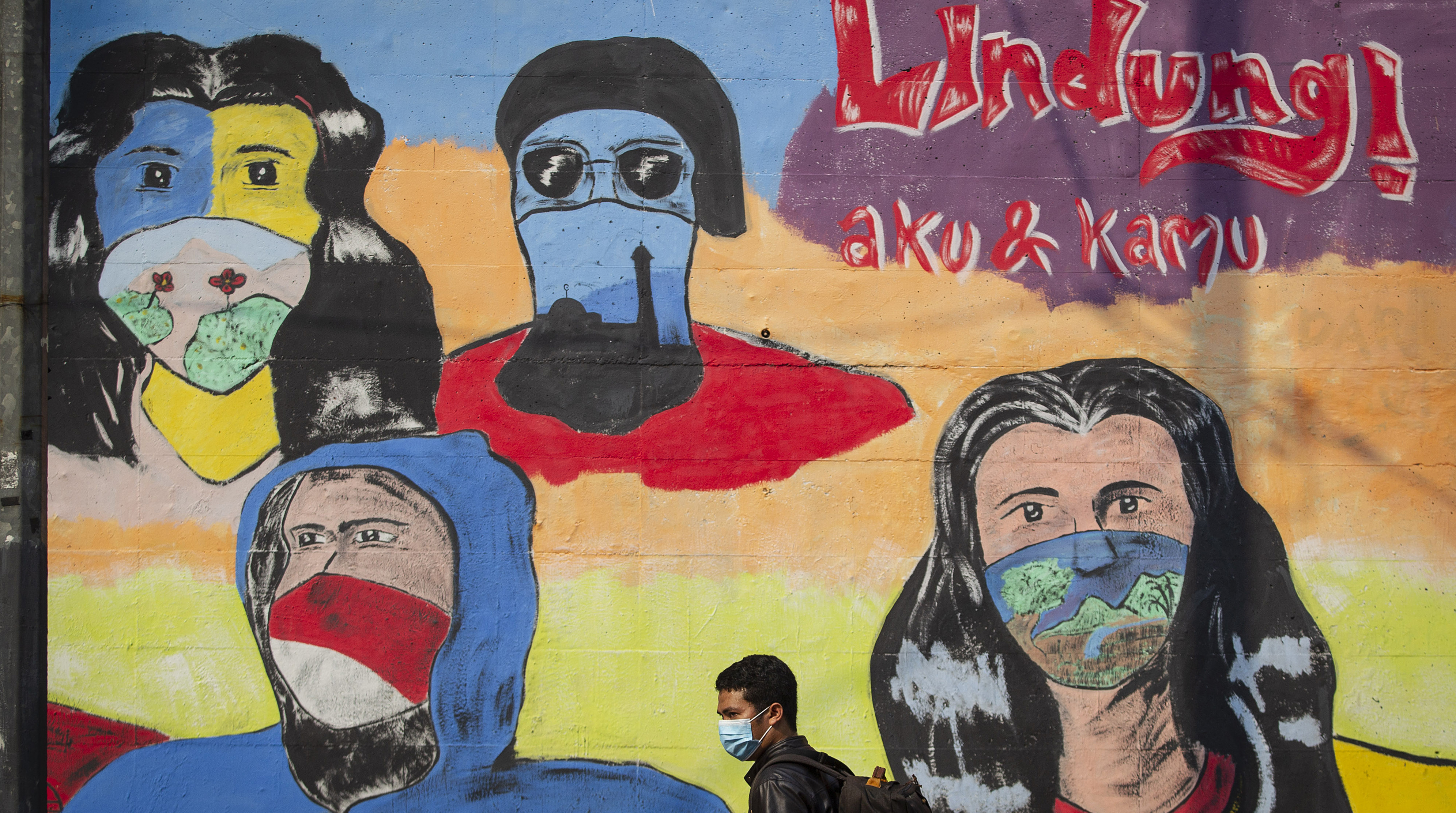 Warga melintas di depan mural berisi pesan ajakan menggunakan masker di kawasan Pancoran, Jakarta, Minggu (18/10/2020).