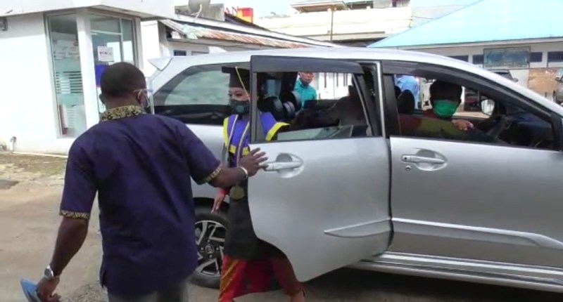 Wisaudawan Universitas Victori menuruni mobil untuk mengikuti wisuda secara drive thru.