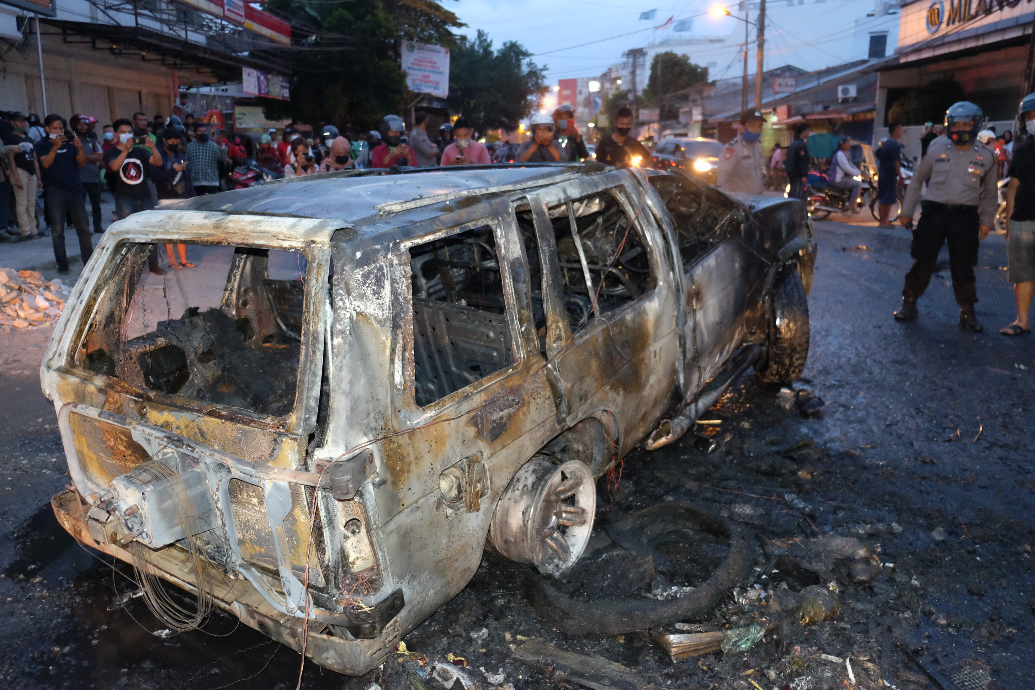 Polisi berjaga di dekat mobil polisi yang dibakar pengunjuk rasa penolak UU Cipta Kerja, di Jalan Sekip, Medan, Sumatera Utara, Kamis (8/10)