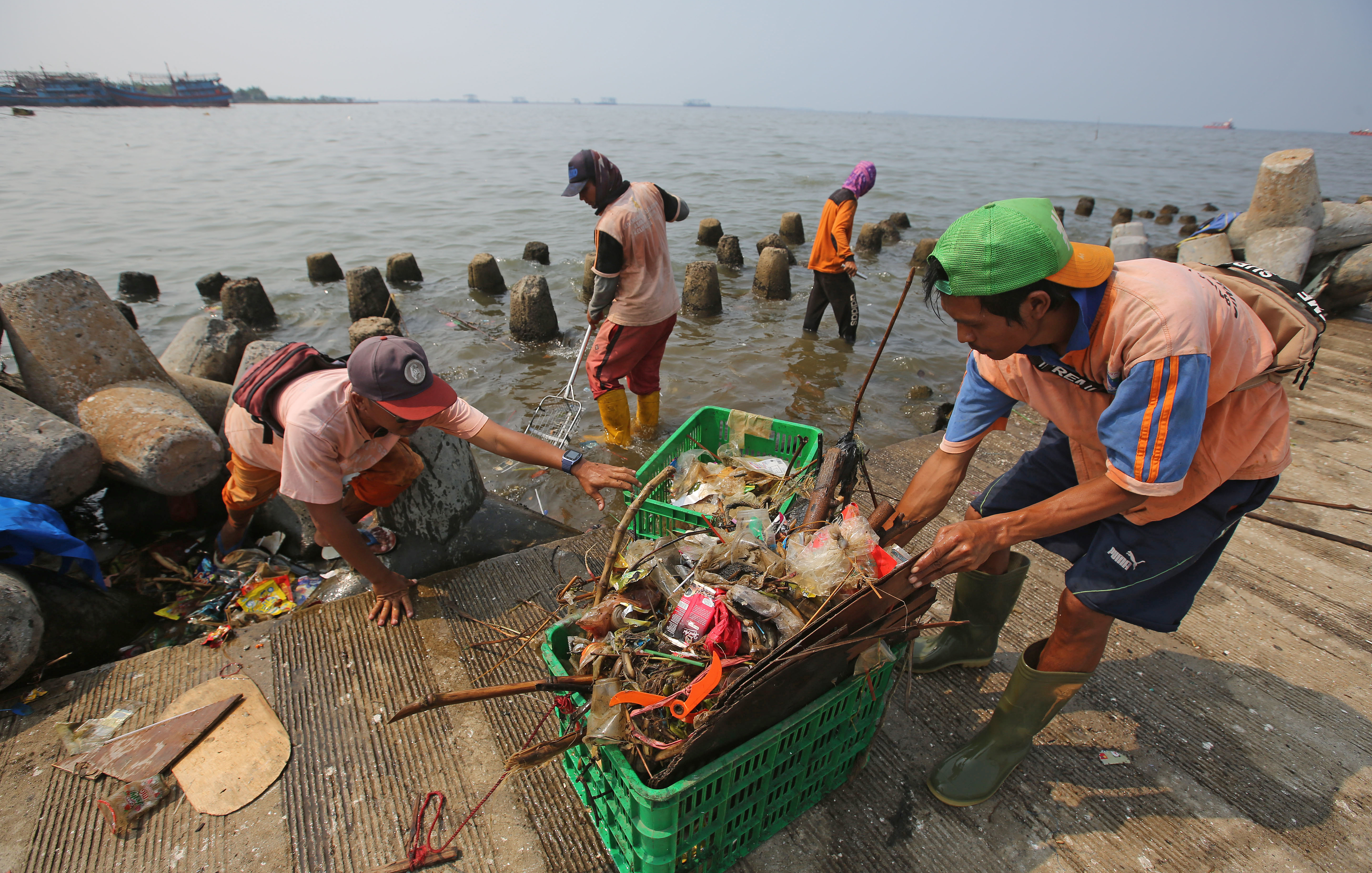 Petugas Suku Dinas Lingkungan Hidup Kepulauan Seribu membersihkan sampah plastik yang terbawa angin Barat Laut di Pelabuhan Kali Adem.