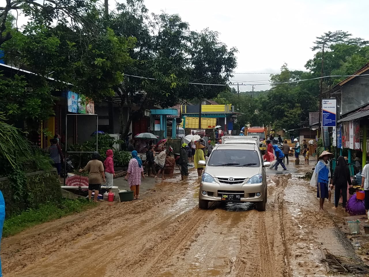 Warga membersihkan lumpur akibat banjir.